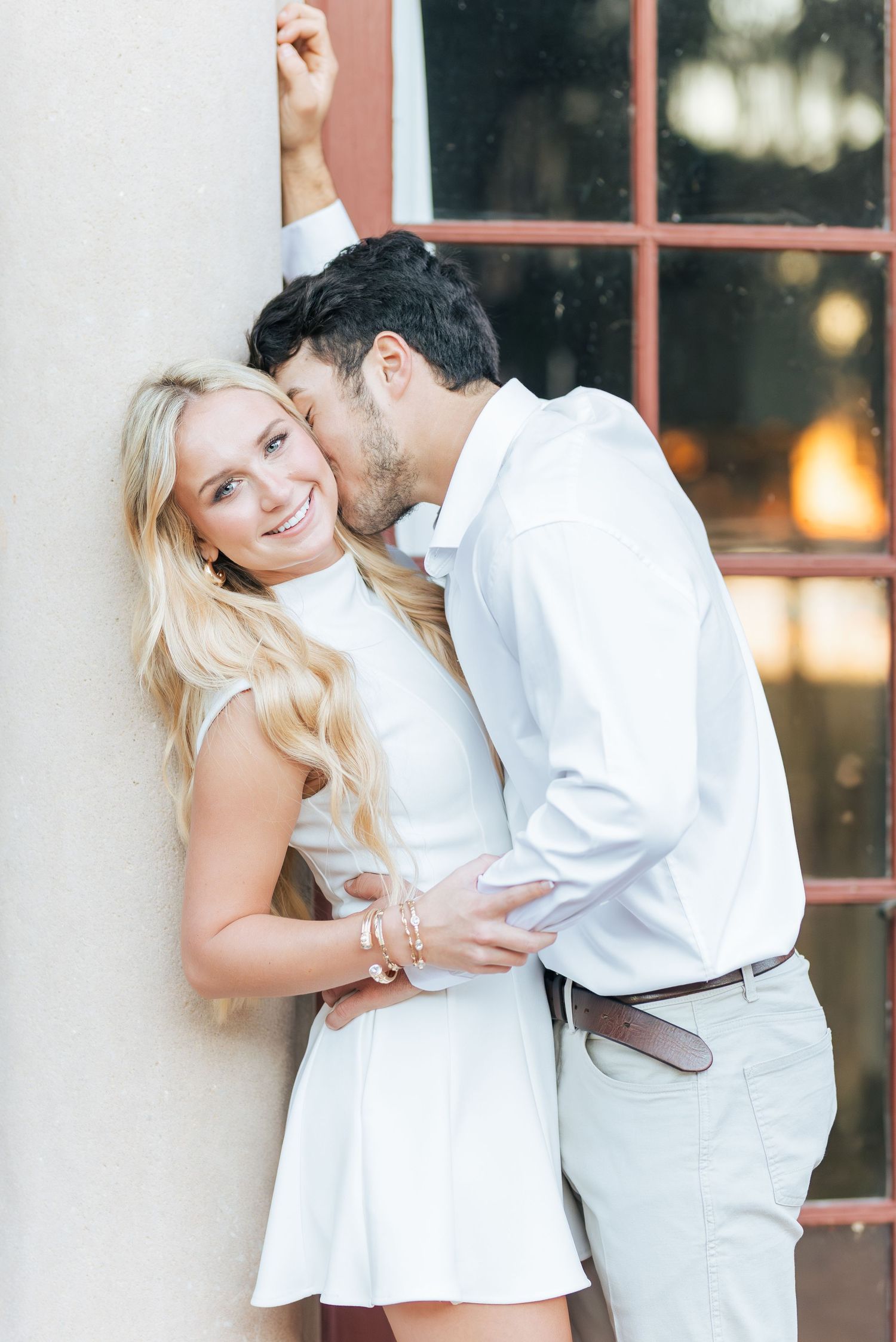 A couple in white and khaki clothing shares sweet moments during their engagement photoshoot.