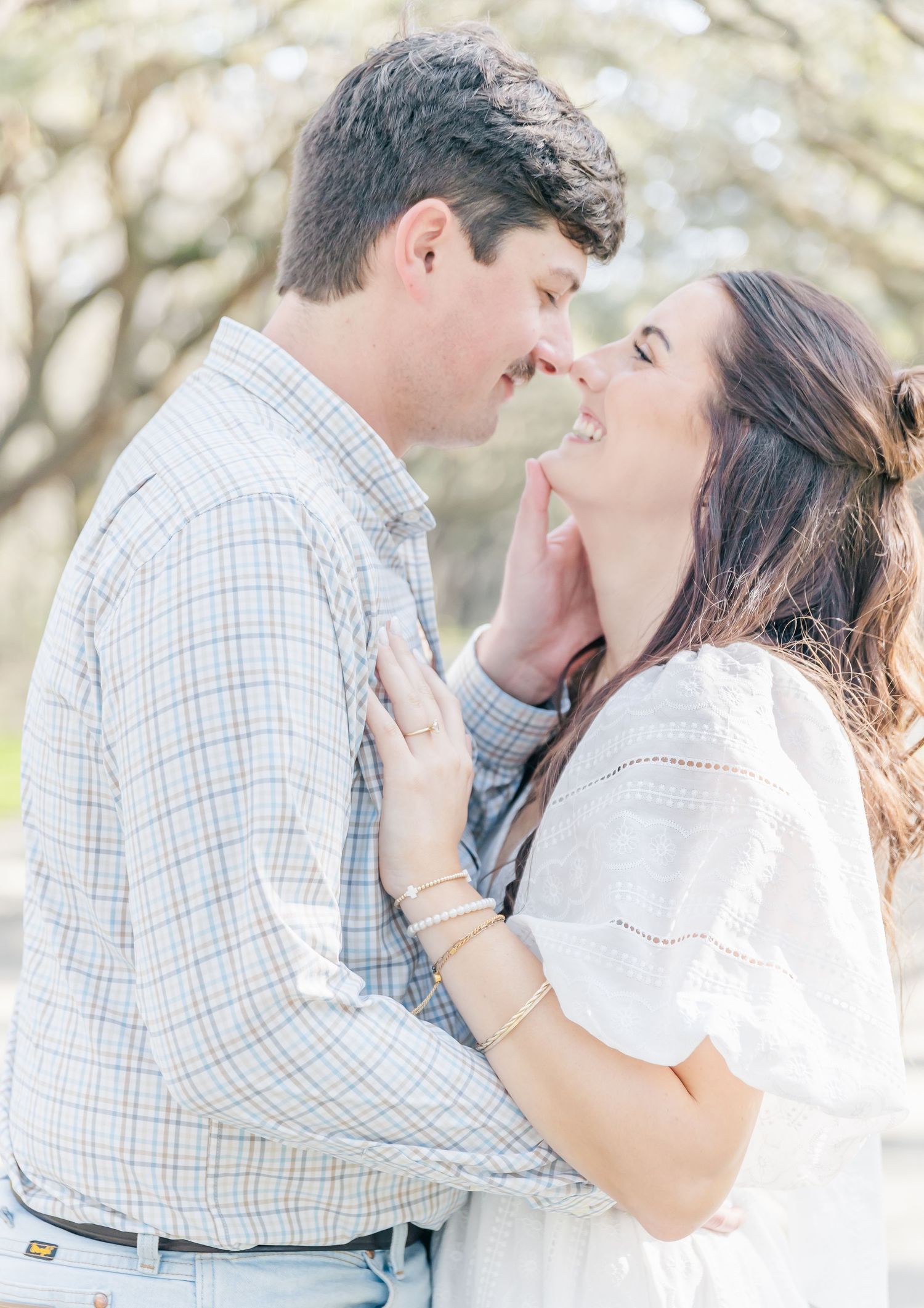 An intimate close-up moment between a couple wearing coordinated light-colored outfits.
