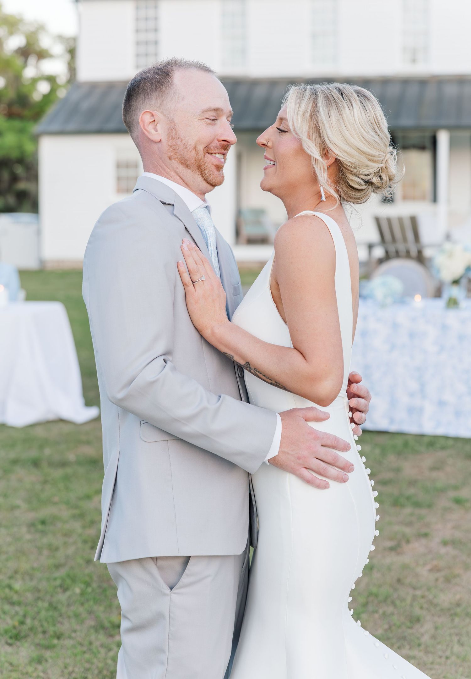 Laughing bride and groom share joyful moment embracing outdoors after wedding ceremony.