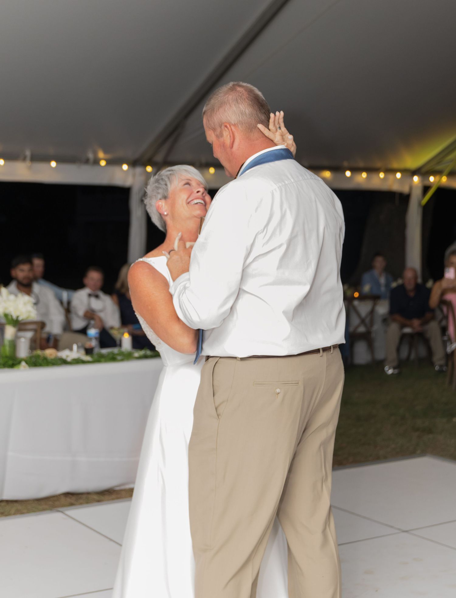 Couple shares a tender moment during their first dance at an outdoor wedding reception.