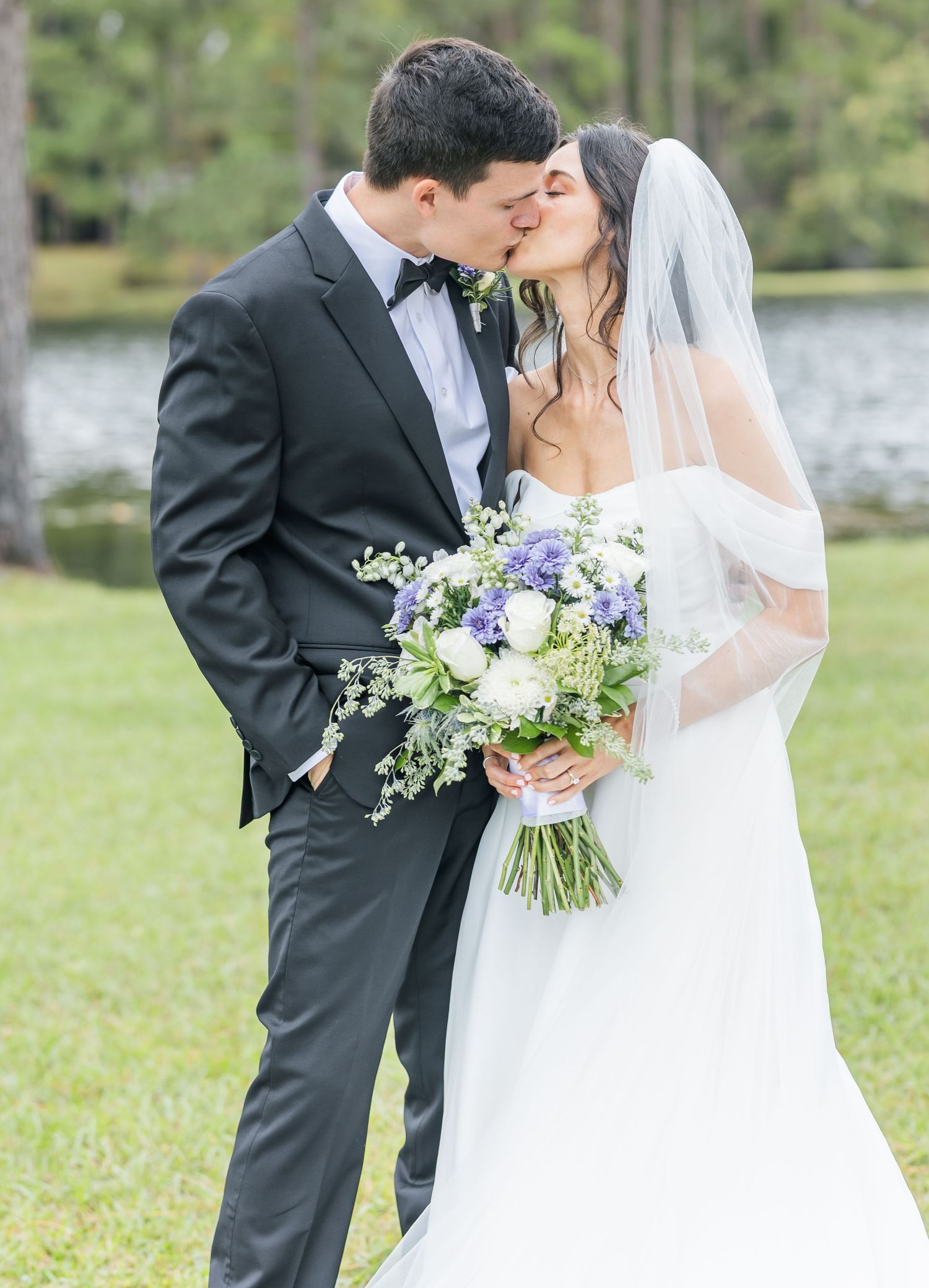 Wedding couple shares intimate moments in an outdoor setting with a beautiful floral bouquet.