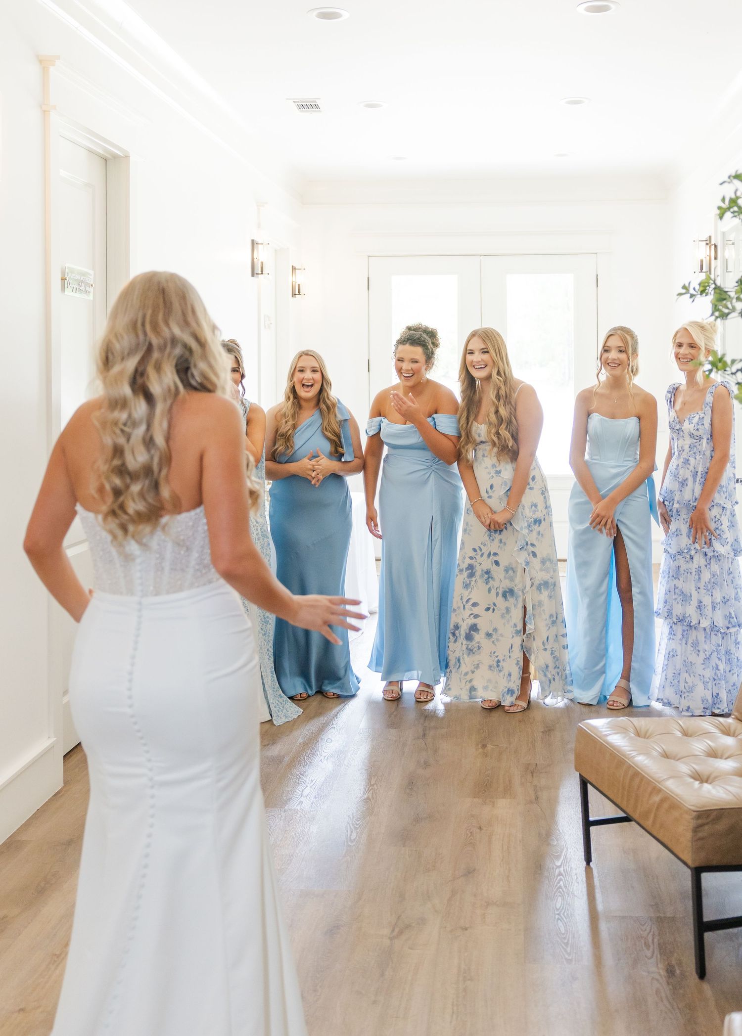 Bride in strapless gown reveals herself to six bridesmaids in blue dresses during emotional first look.