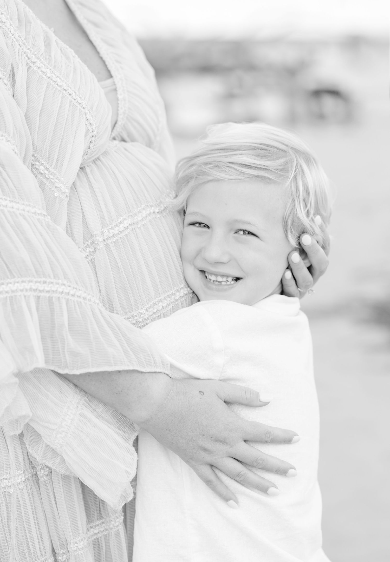 A tender moment captured in black and white as a child embraces an adult wearing a striped top.