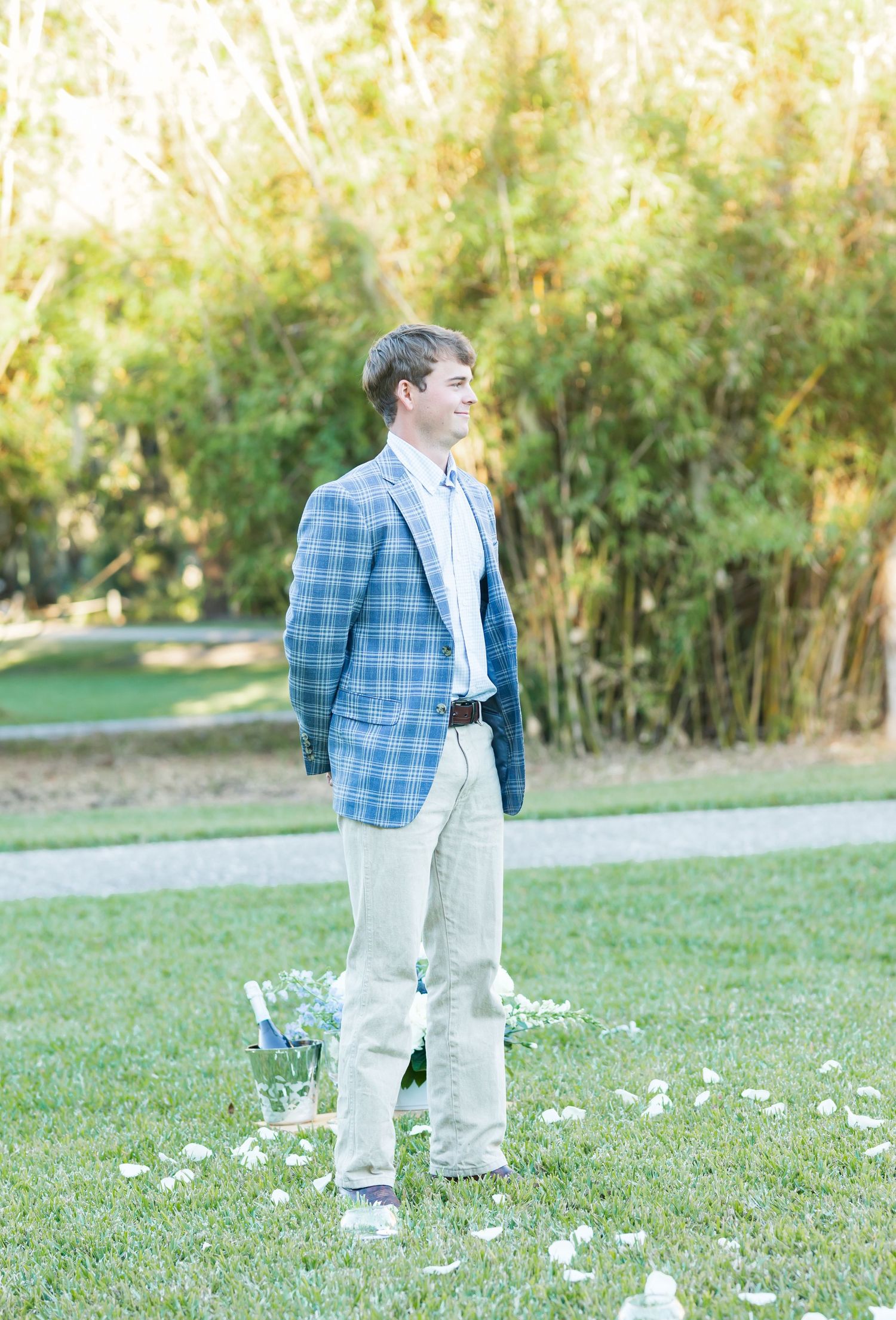 A couple shares a joyful moment in a sunny park while surrounded by scattered white flower petals.