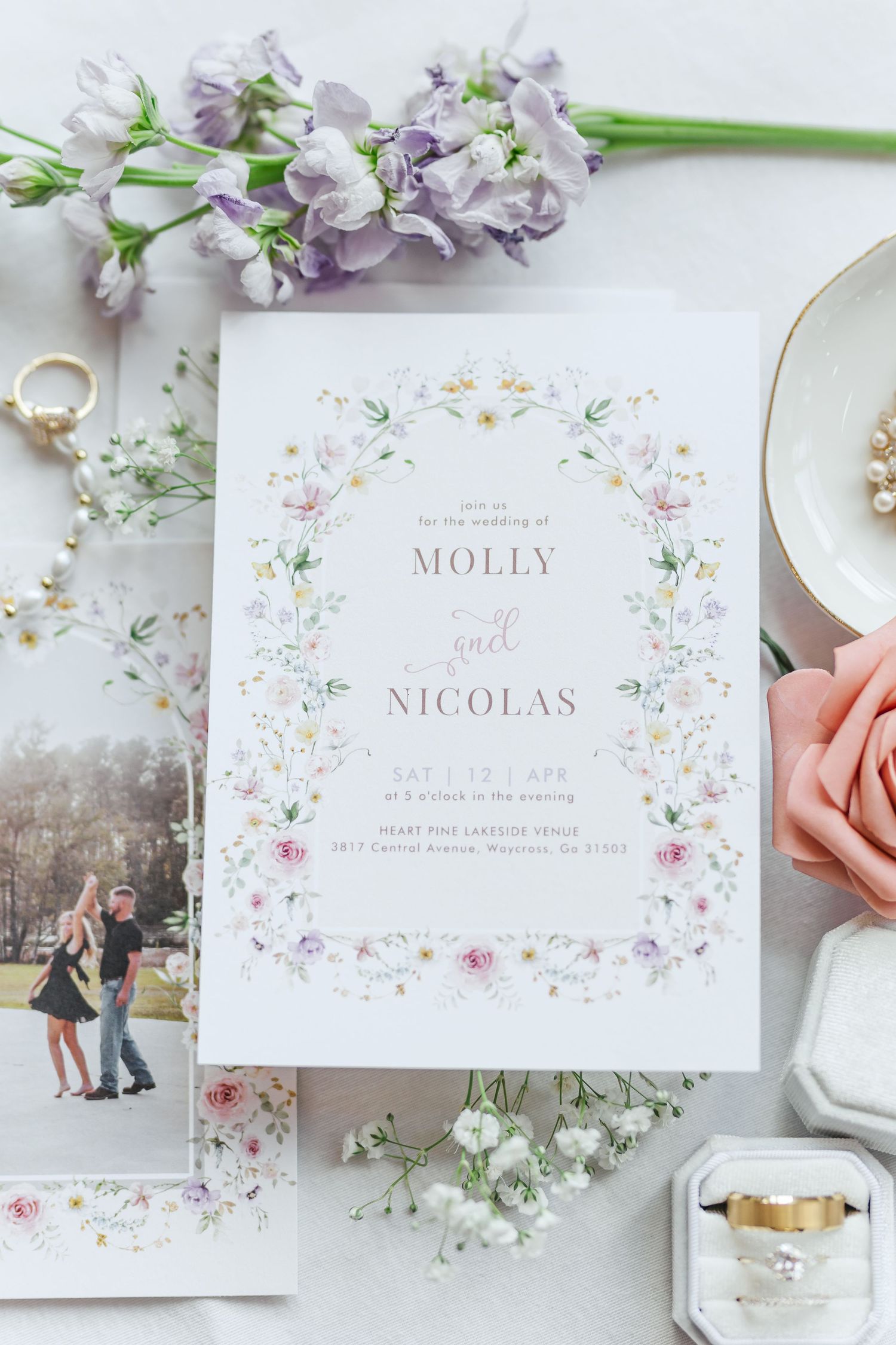 Elegant wedding invitation with purple flowers and engagement photos styled with roses.