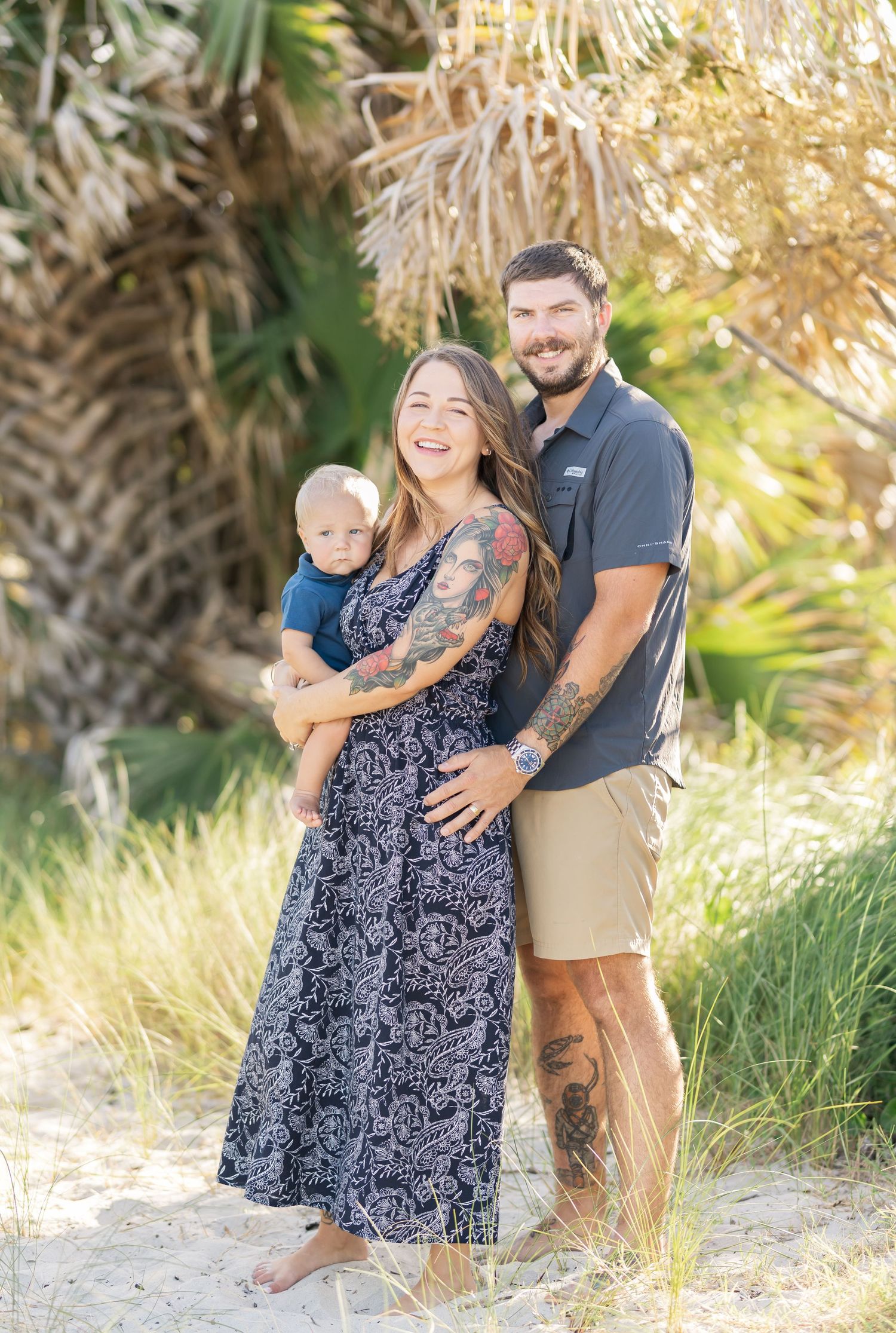 Romantic outdoor photoshoot with couple embracing by palm trees on a sunny beach path.