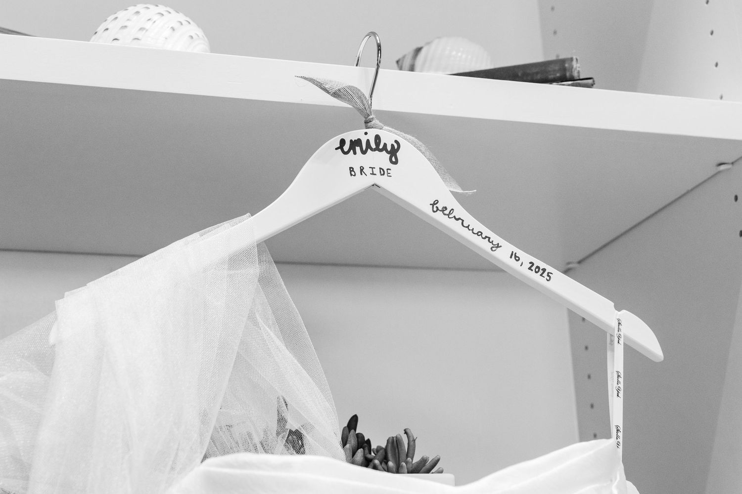 White wedding dress details hanging in bridal preparation room.