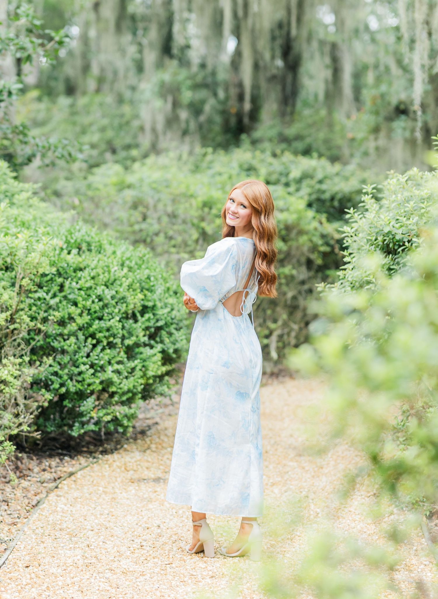A series of dreamy outdoor photos in a lush garden path showing someone in a flowing white dress dancing and twirling.