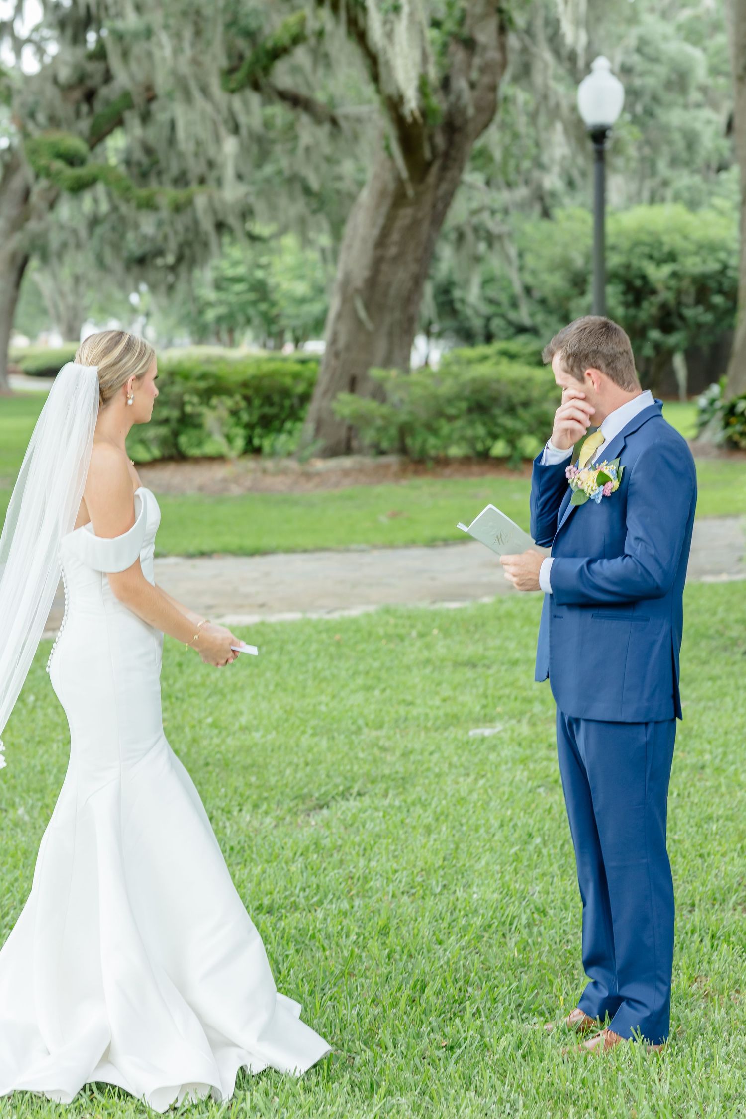 A couple shares a playful first look moment in a garden setting with the bride twirling in her white gown.