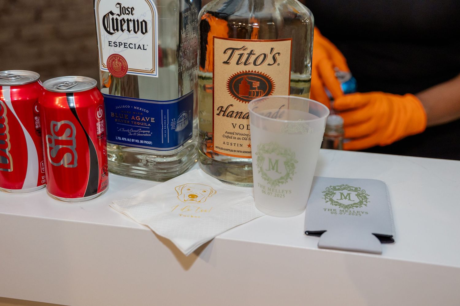 Bar setup at wedding reception with various liquor bottles including Corona and Tito's vodka.