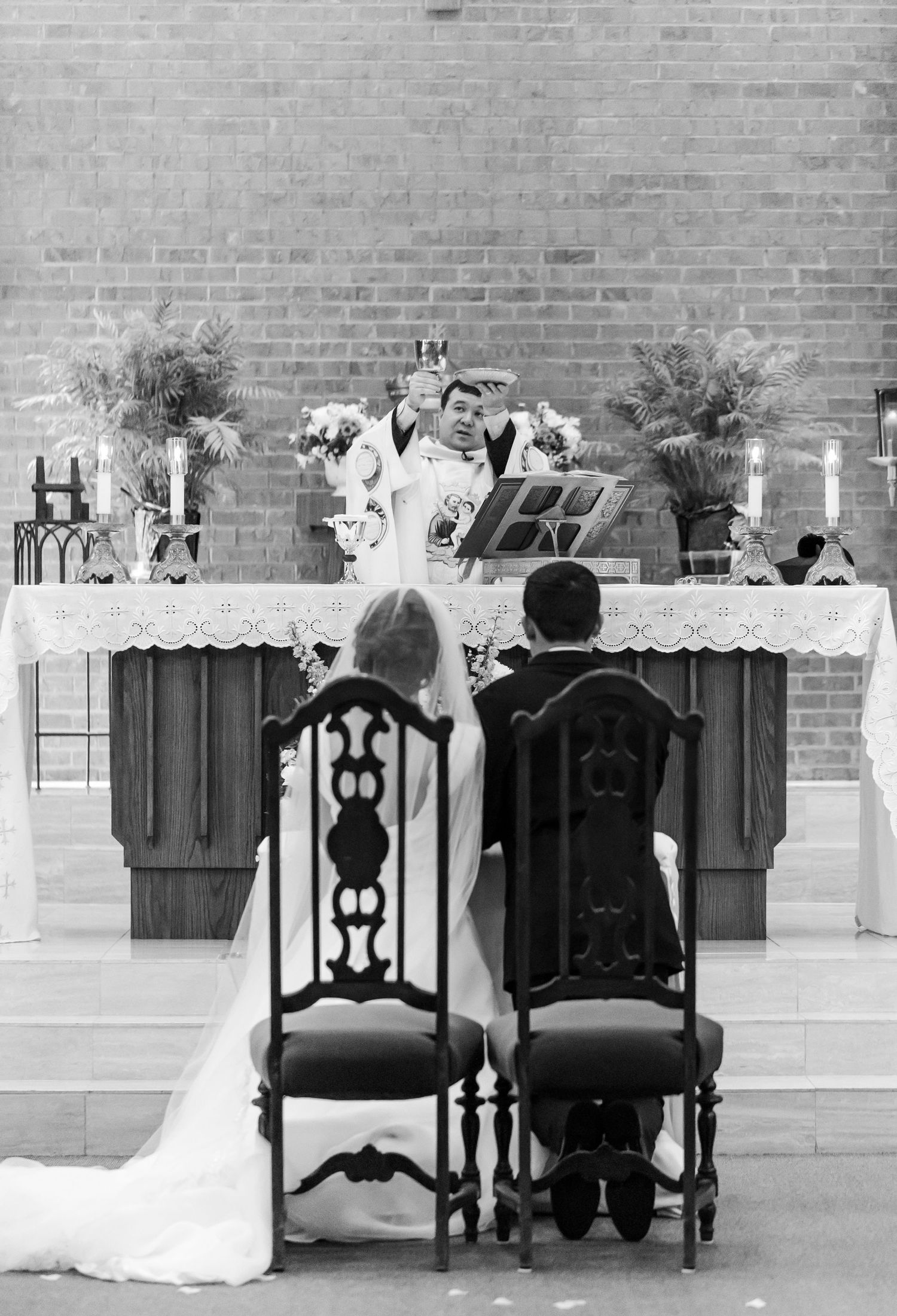 Black and white photo of decorated church altar with ornate chairs.