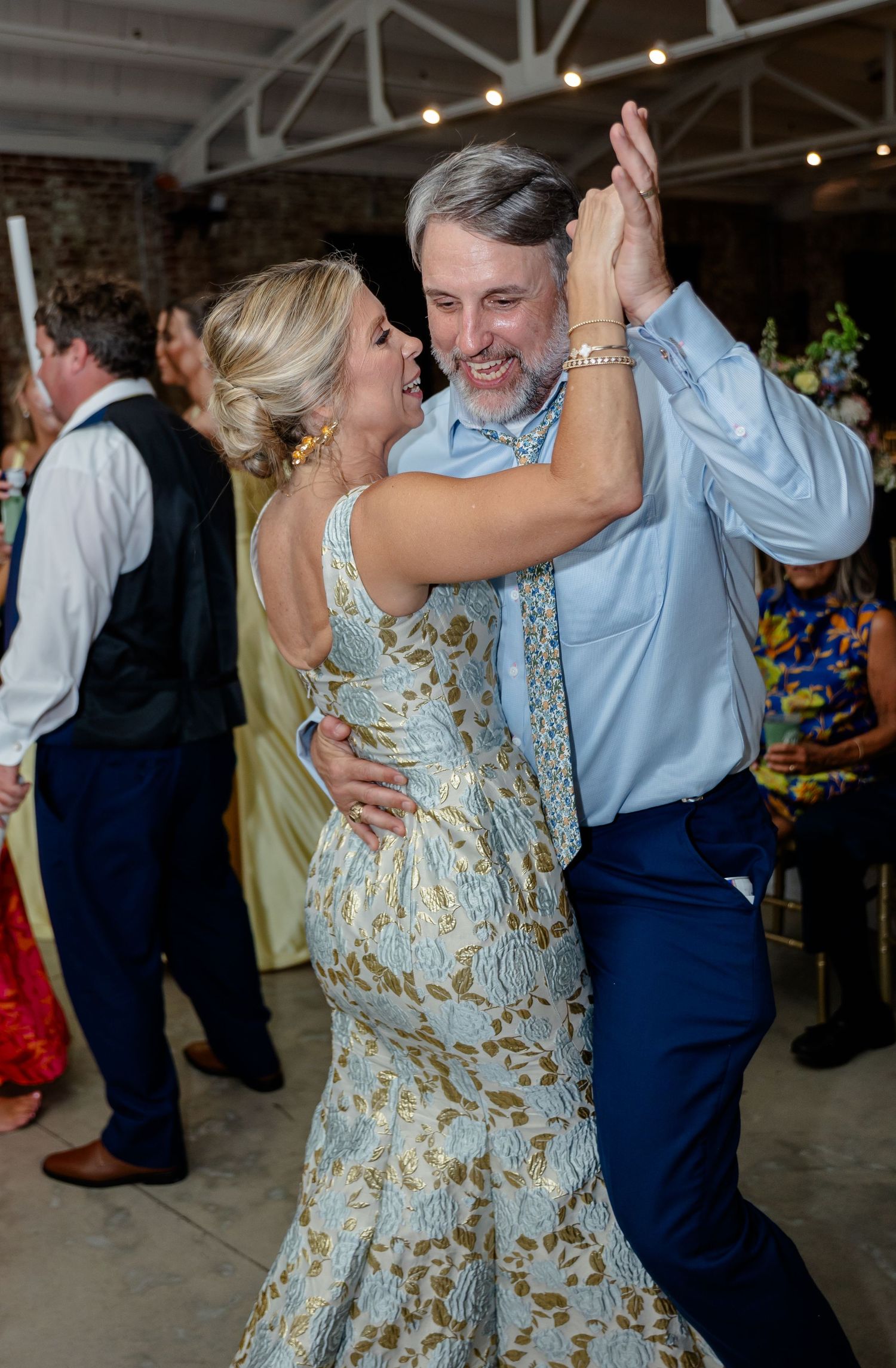 Dancers in formal attire enjoy a lively moment on the dance floor at an indoor event.