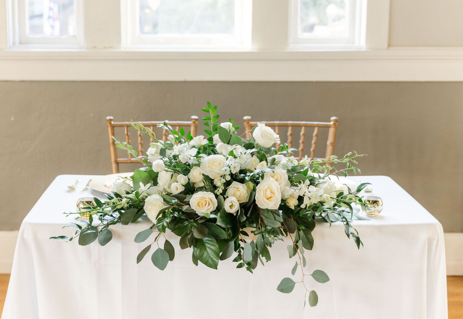 Wedding reception tables decorated with white linens and lush floral centerpieces.