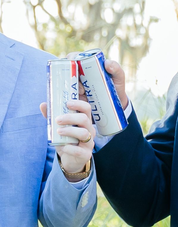 Hand holding a blue and white Pepsi can against a blurred outdoor background.
