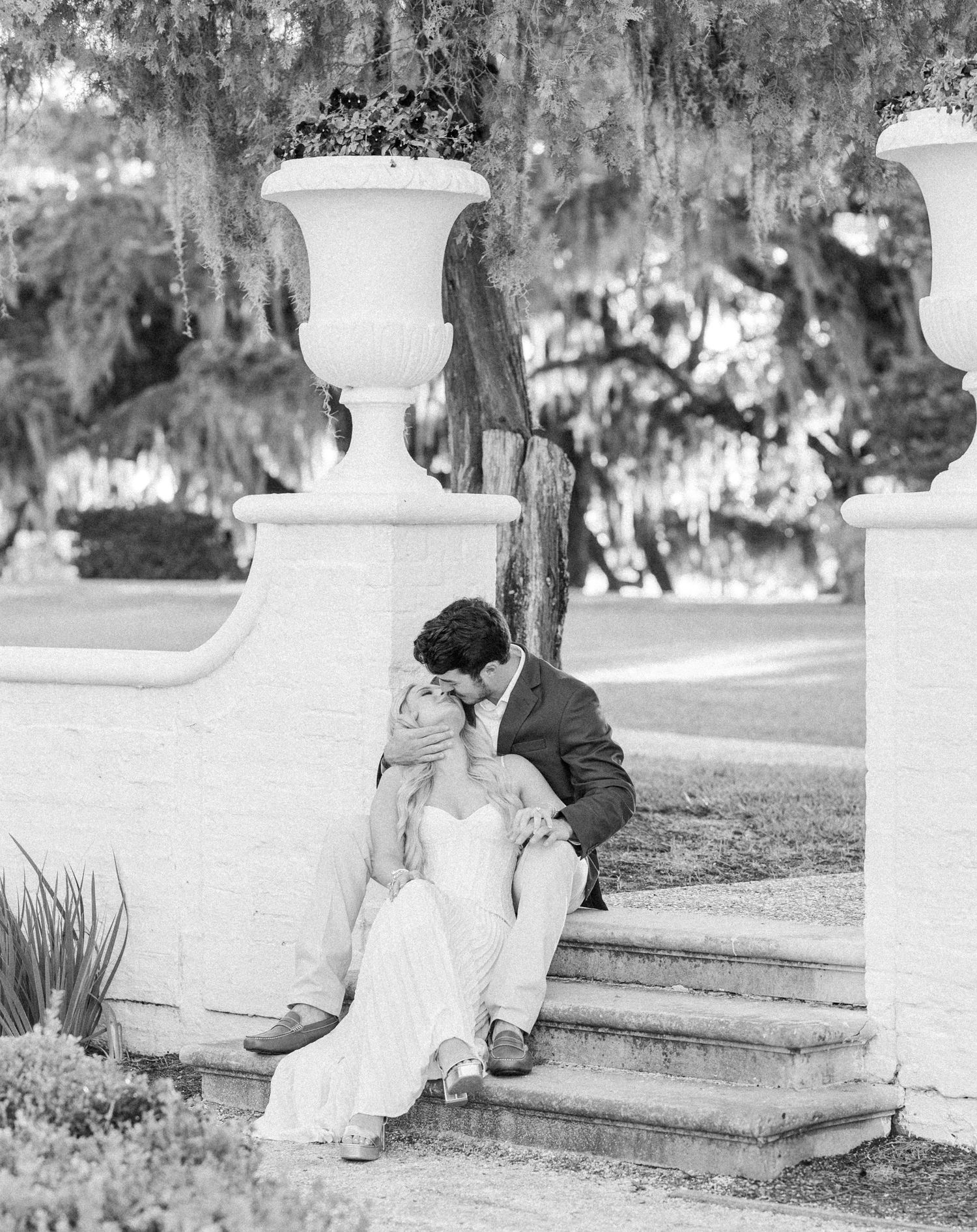 Black and white photo series of a couple sitting on white stone steps in a romantic setting.