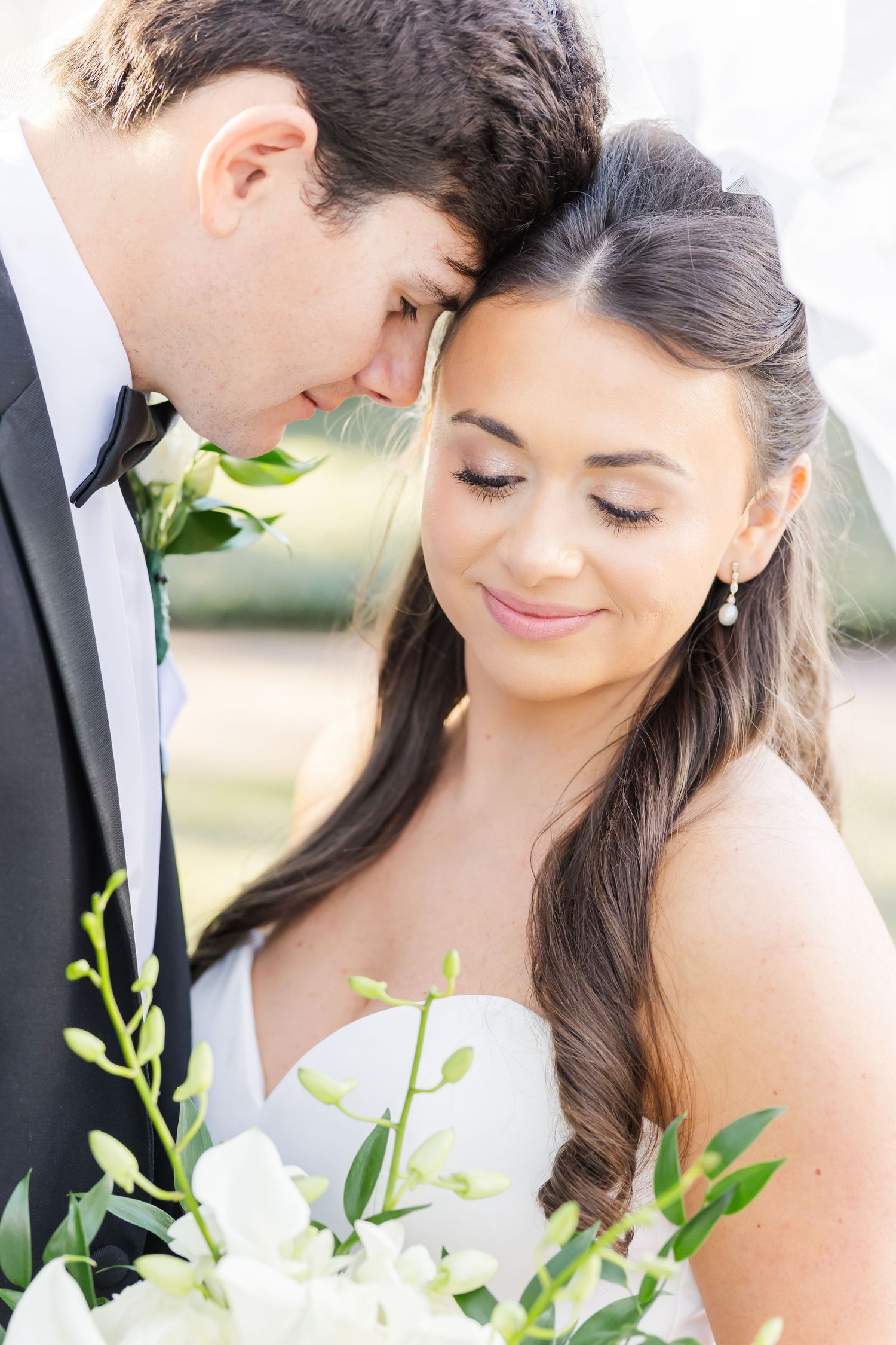 Romantic wedding portraits showing bride with flowing dark hair holding delicate green bouquet.