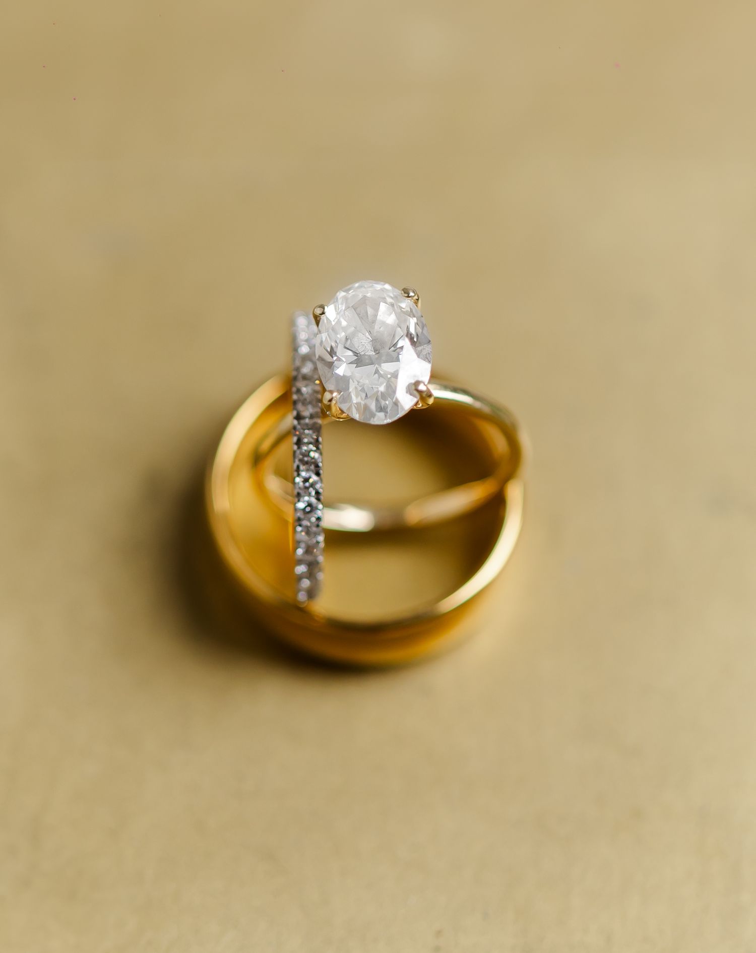 Gold engagement ring with diamond solitaire photographed against beige background.