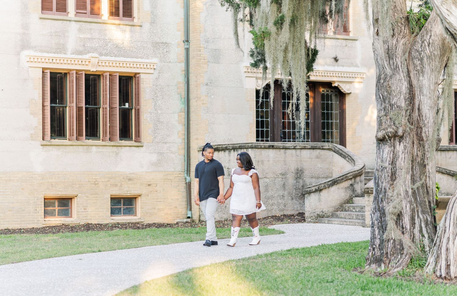 Panoramic view of a historic stone building exterior with wooden windows and a grassy lawn.