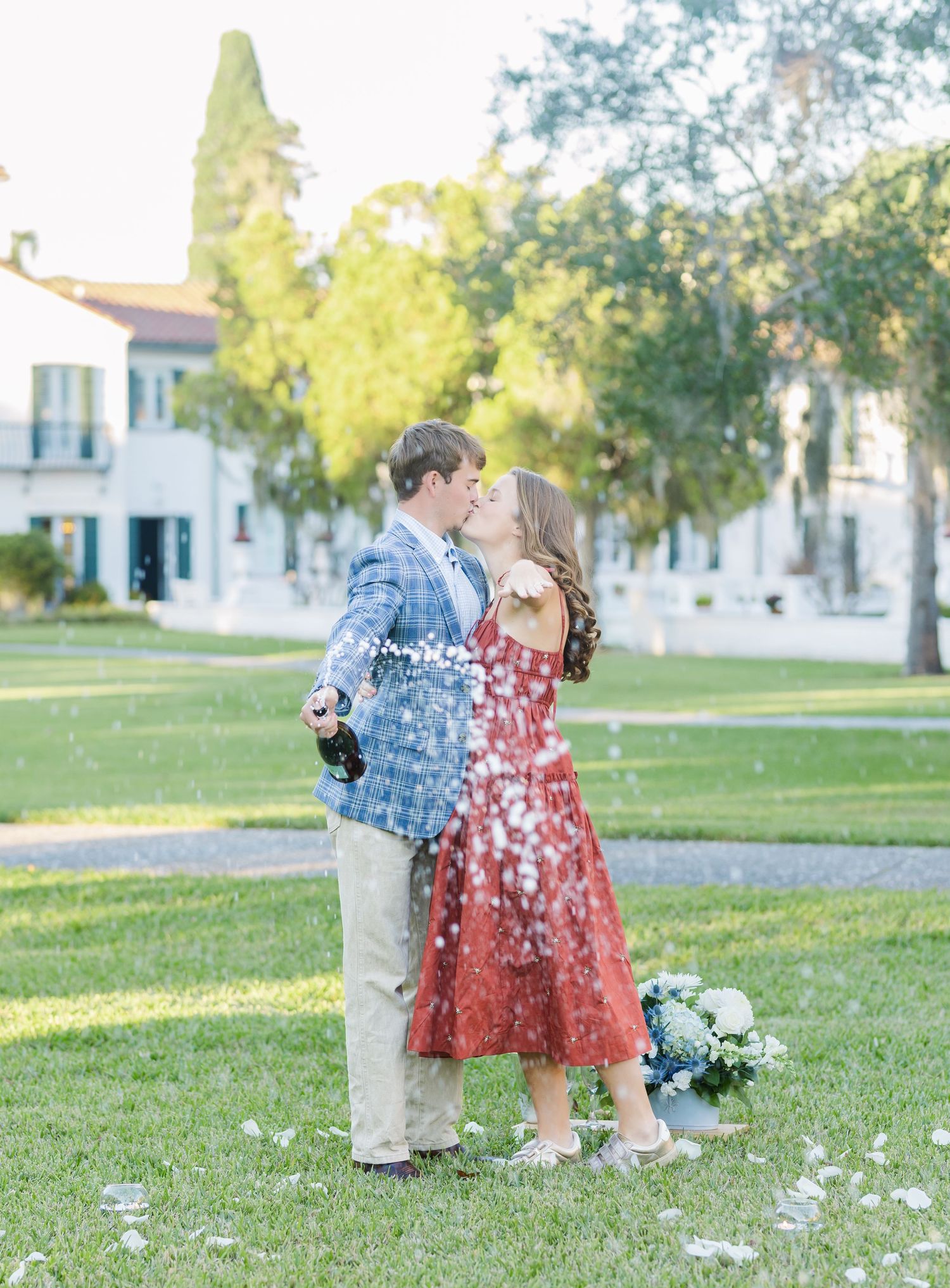 Romantic couple in coordinated outfits sharing a sweet moment on a grassy lawn.