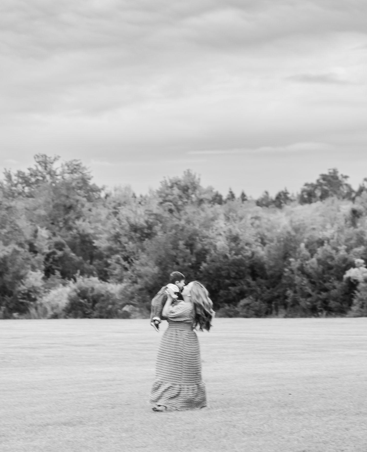 Black and white photo series showing intimate moments in an open field with trees in the background.