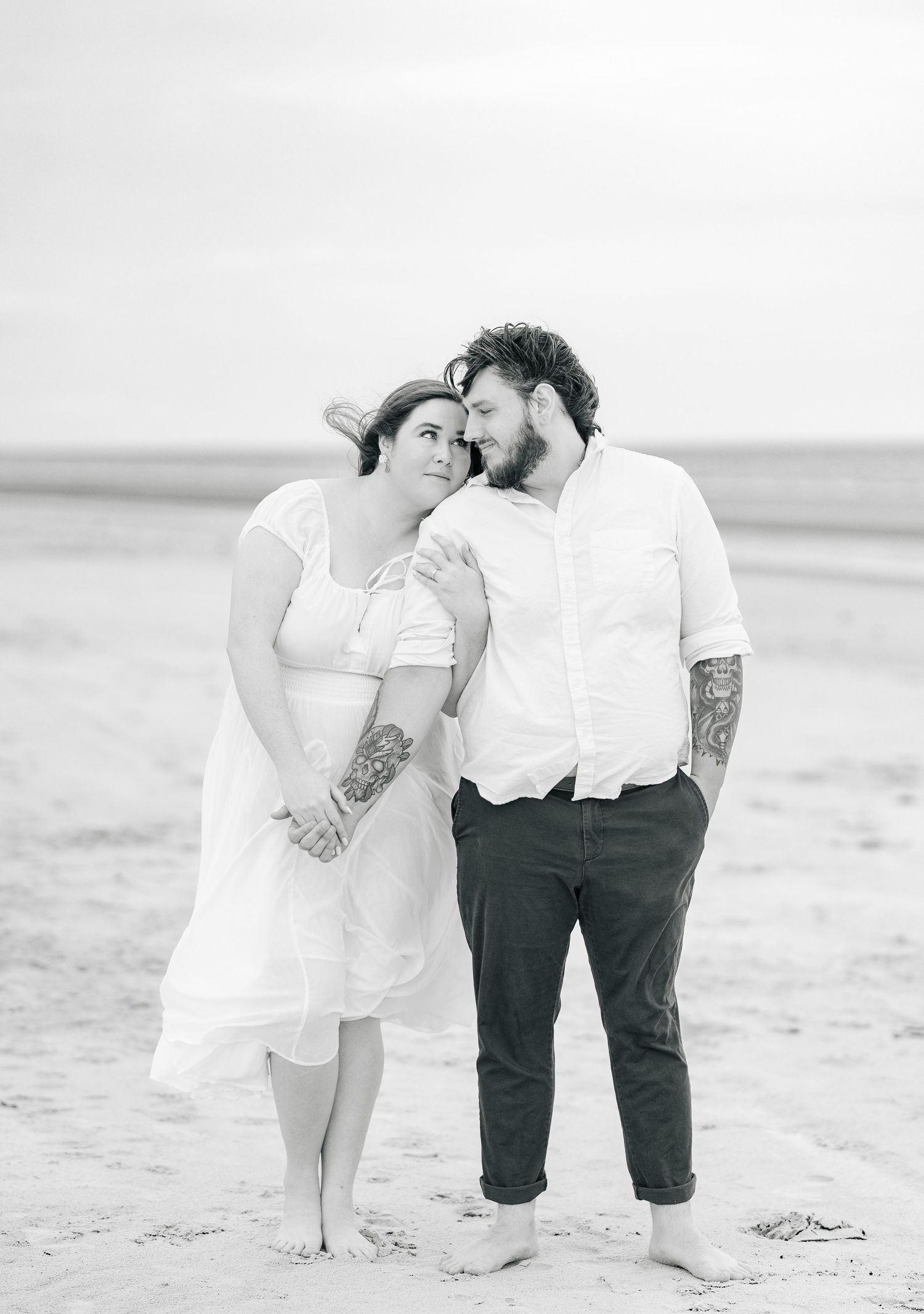 Black and white beach portrait of a couple in romantic formal wear.