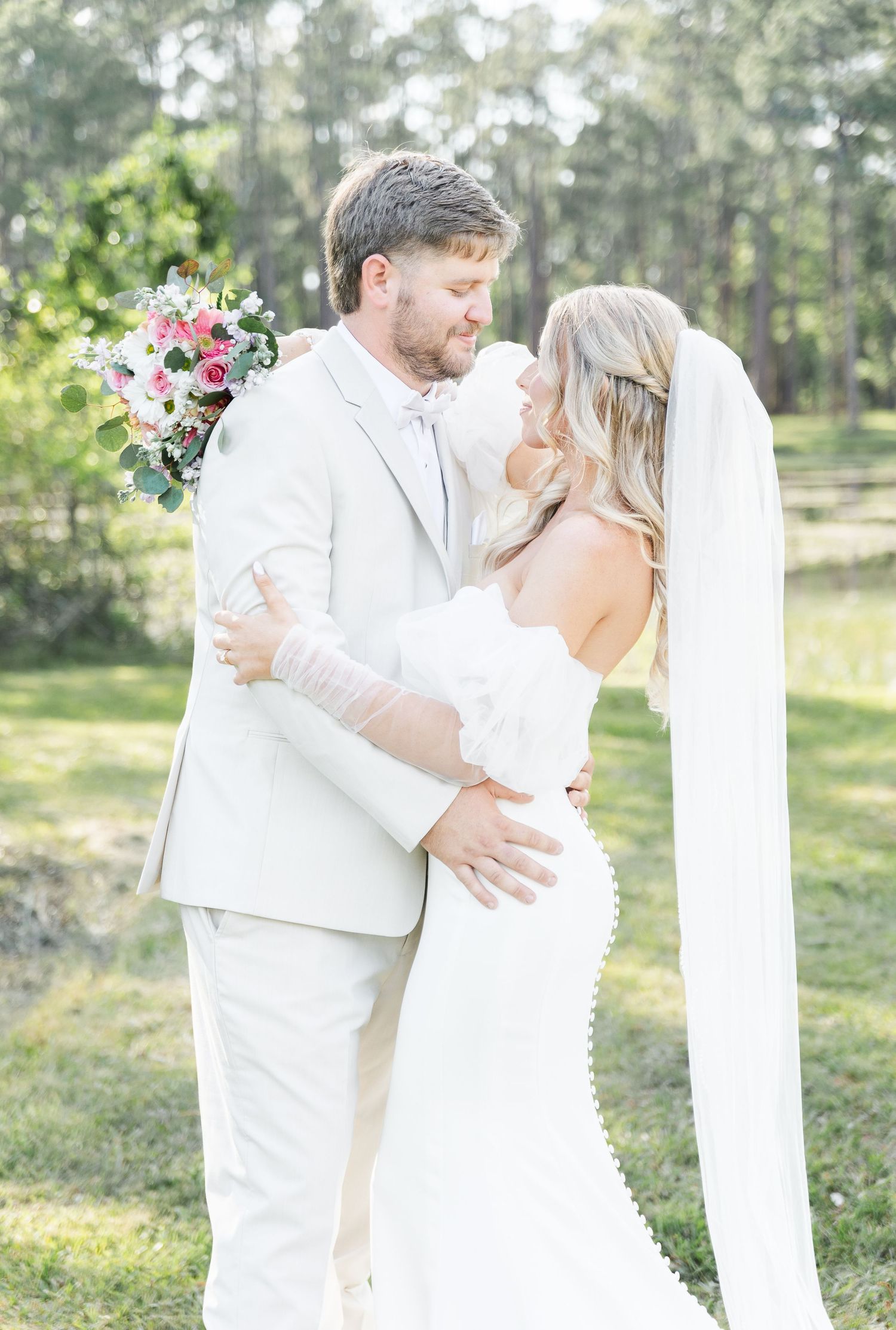 Elegant wedding couple shares an intimate moment in a scenic outdoor garden setting.