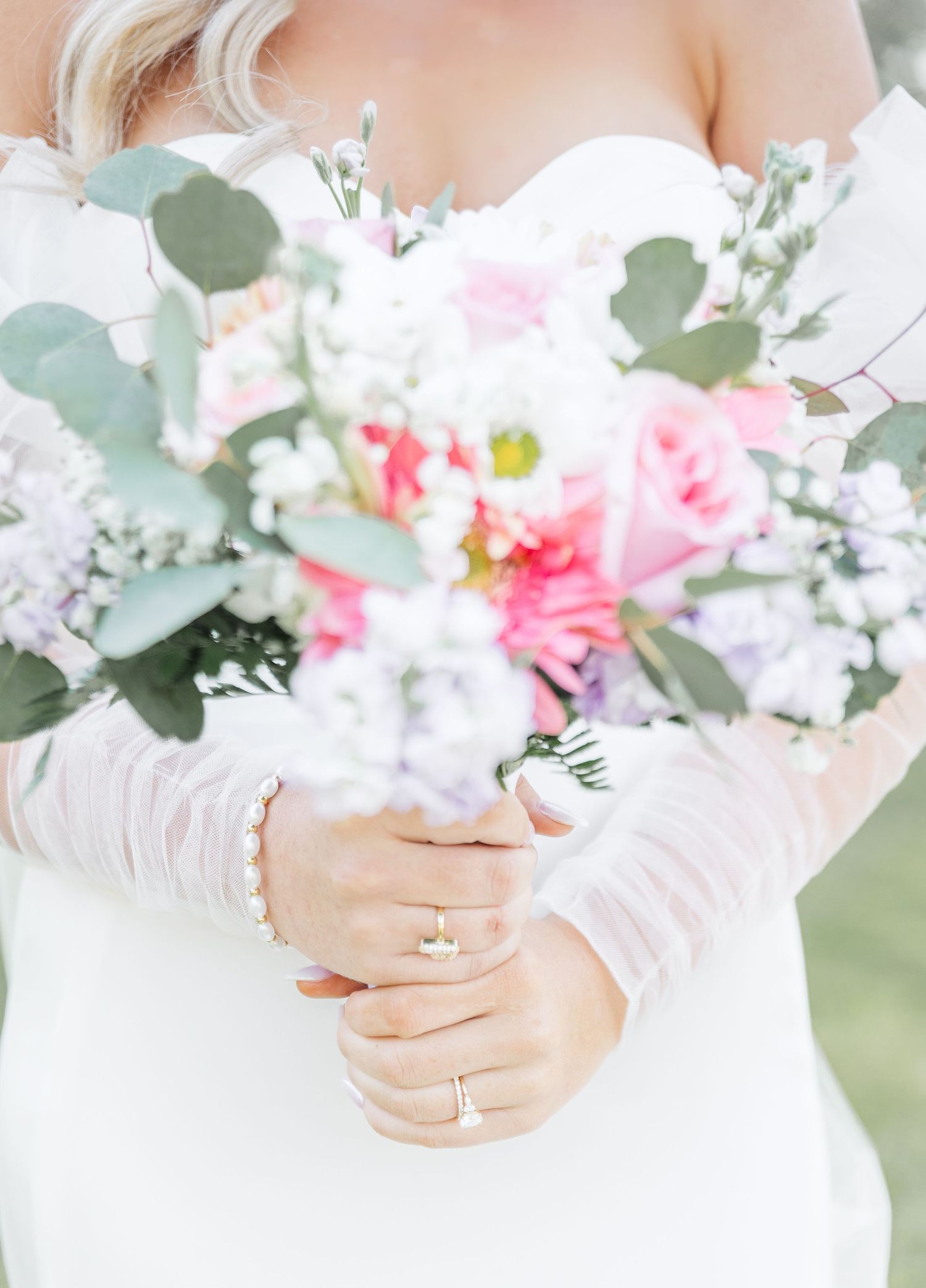 Close-up of bridal bouquet with pink roses, white flowers, and eucalyptus leaves.