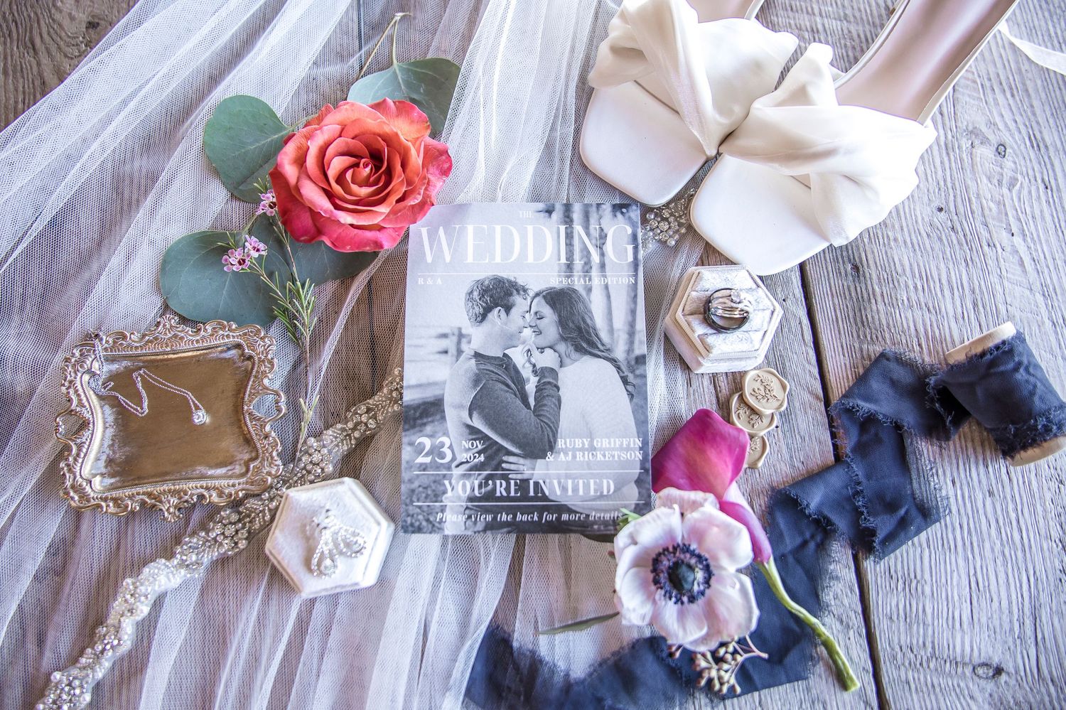 Wedding flatlay with roses, vintage frames, ring box and delicate silk ribbons.