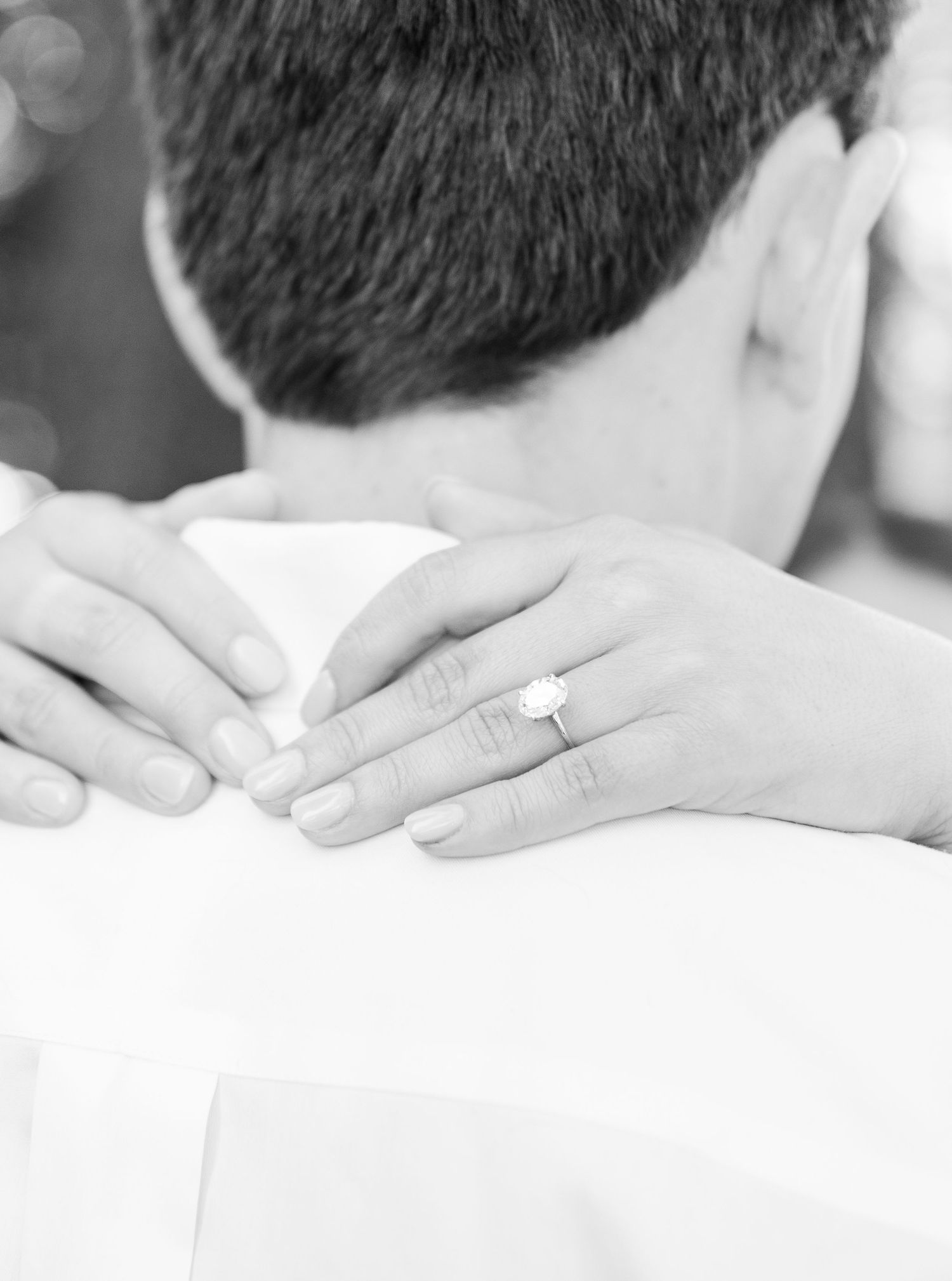 Close-up black and white shot of hands with engagement ring.