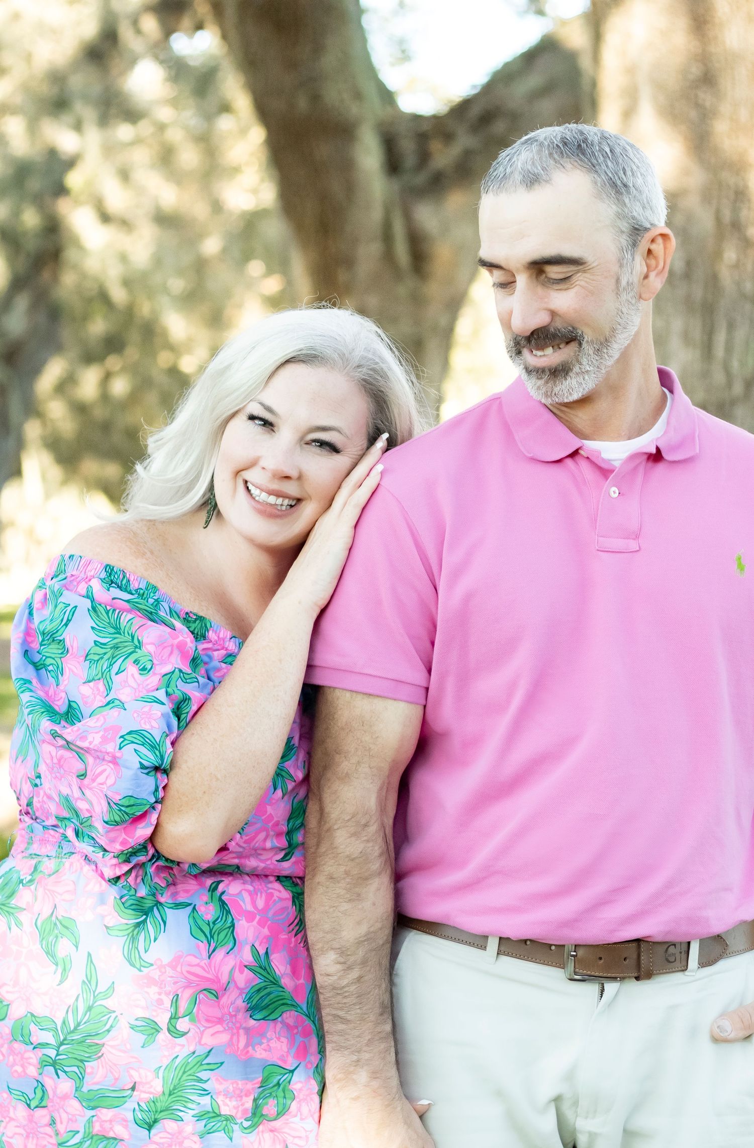 Summer portrait of couple in pink polo and floral dress outdoors.