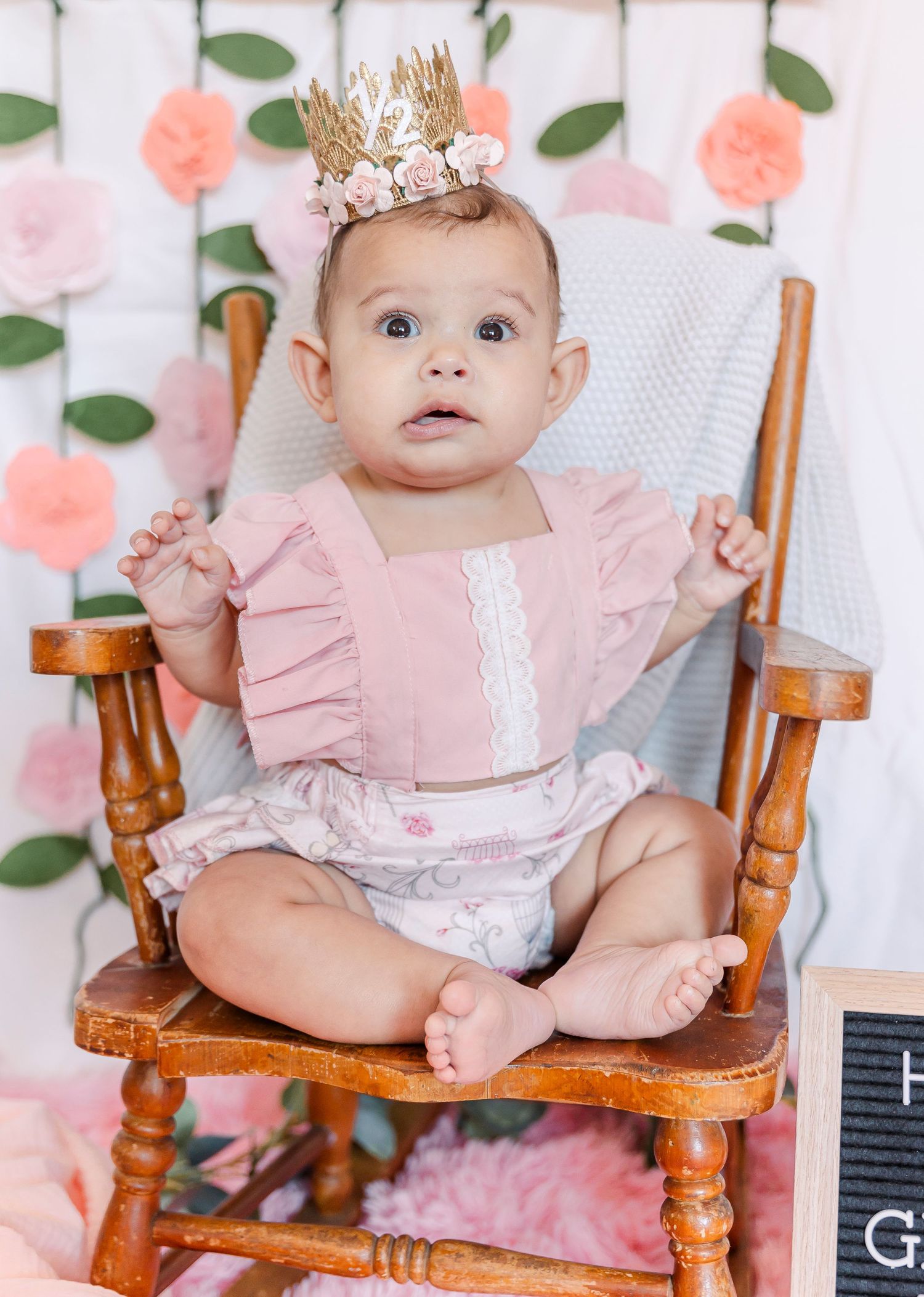 Baby milestone photo with letterboard sign reading 'Half a year growing like a wildflower'.