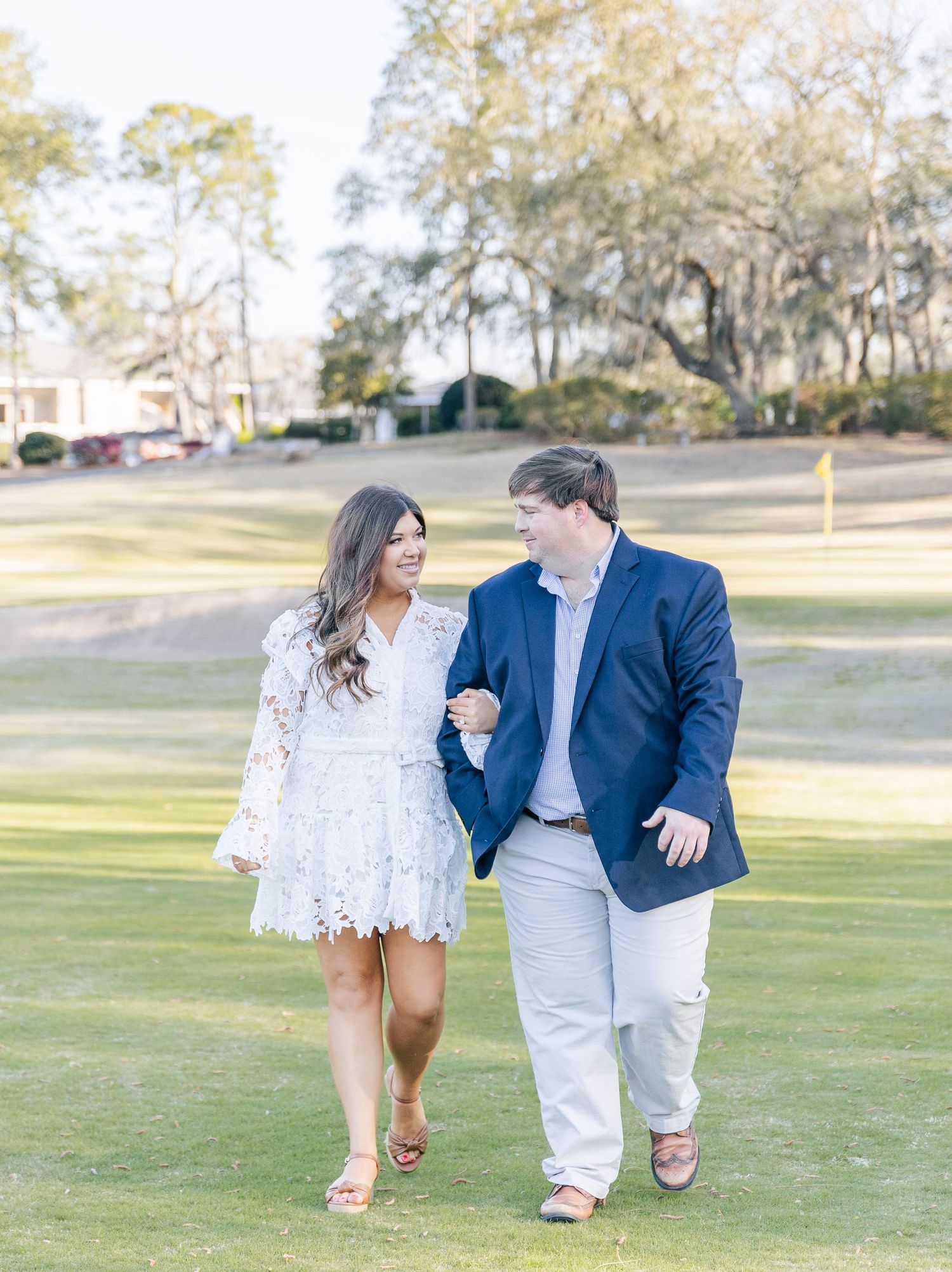 Engaged couple taking a romantic stroll on a golf course.