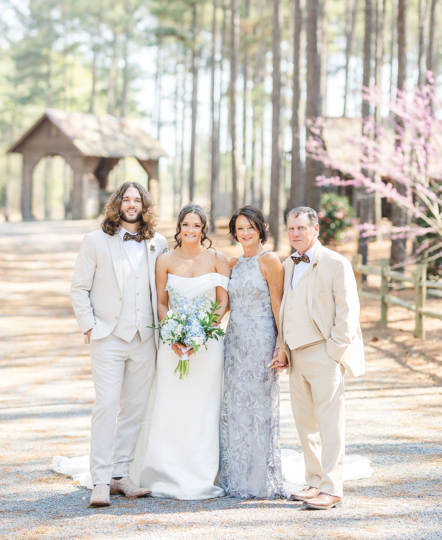Wedding party poses outdoors with bride in white gown, bridesmaids in yellow, and groomsmen in tan suits.