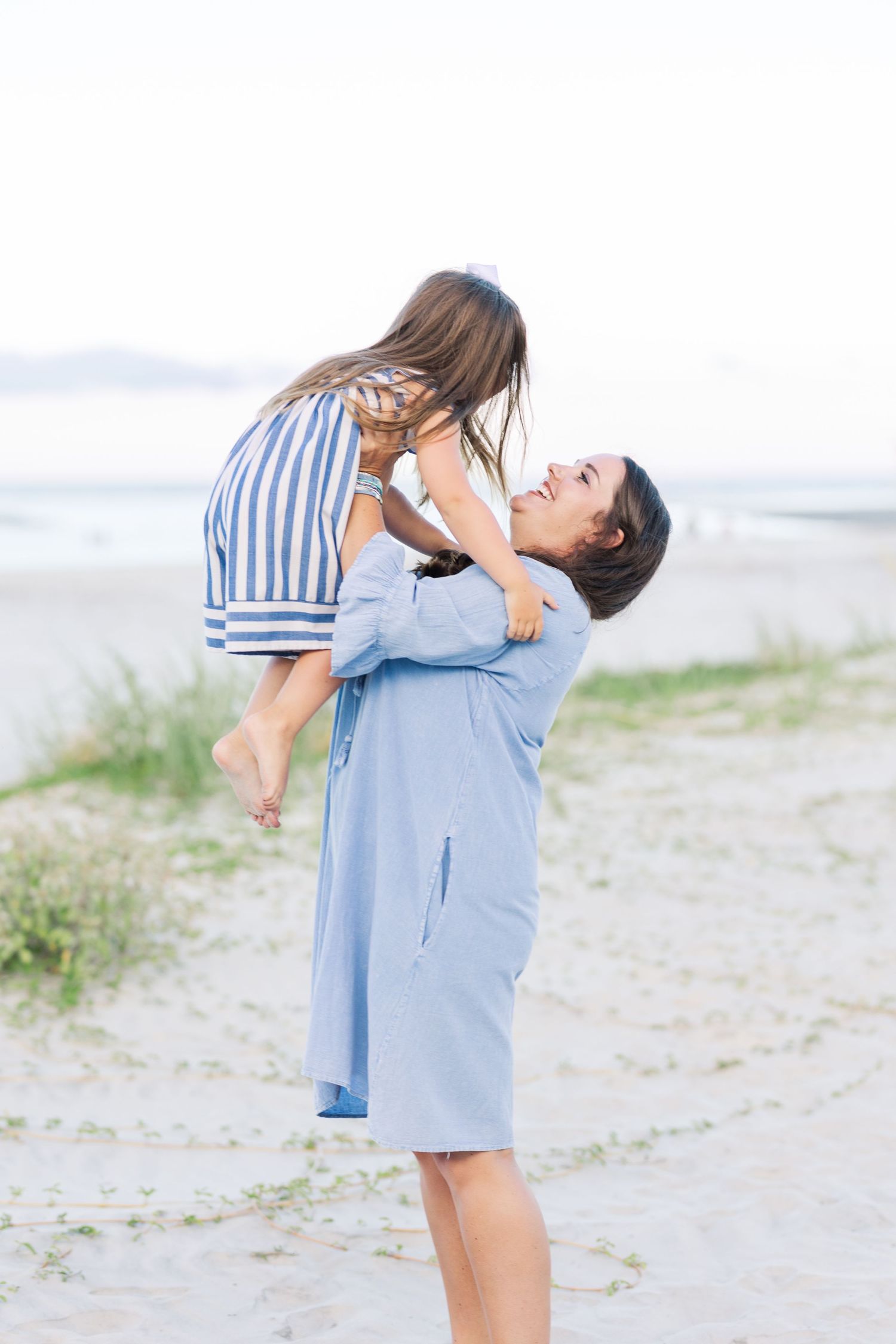 A touching moment captured as one person lifts another in a joyful embrace on the beach.
