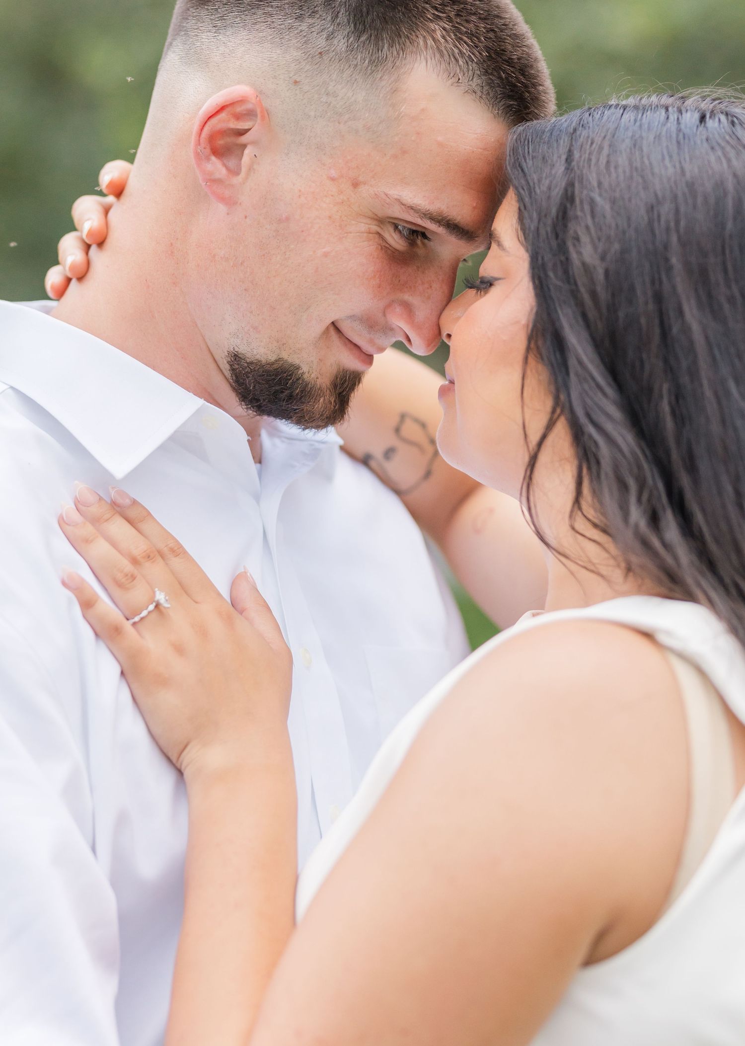 Close-up of romantic couple nearly kissing, woman showing diamond engagement ring.