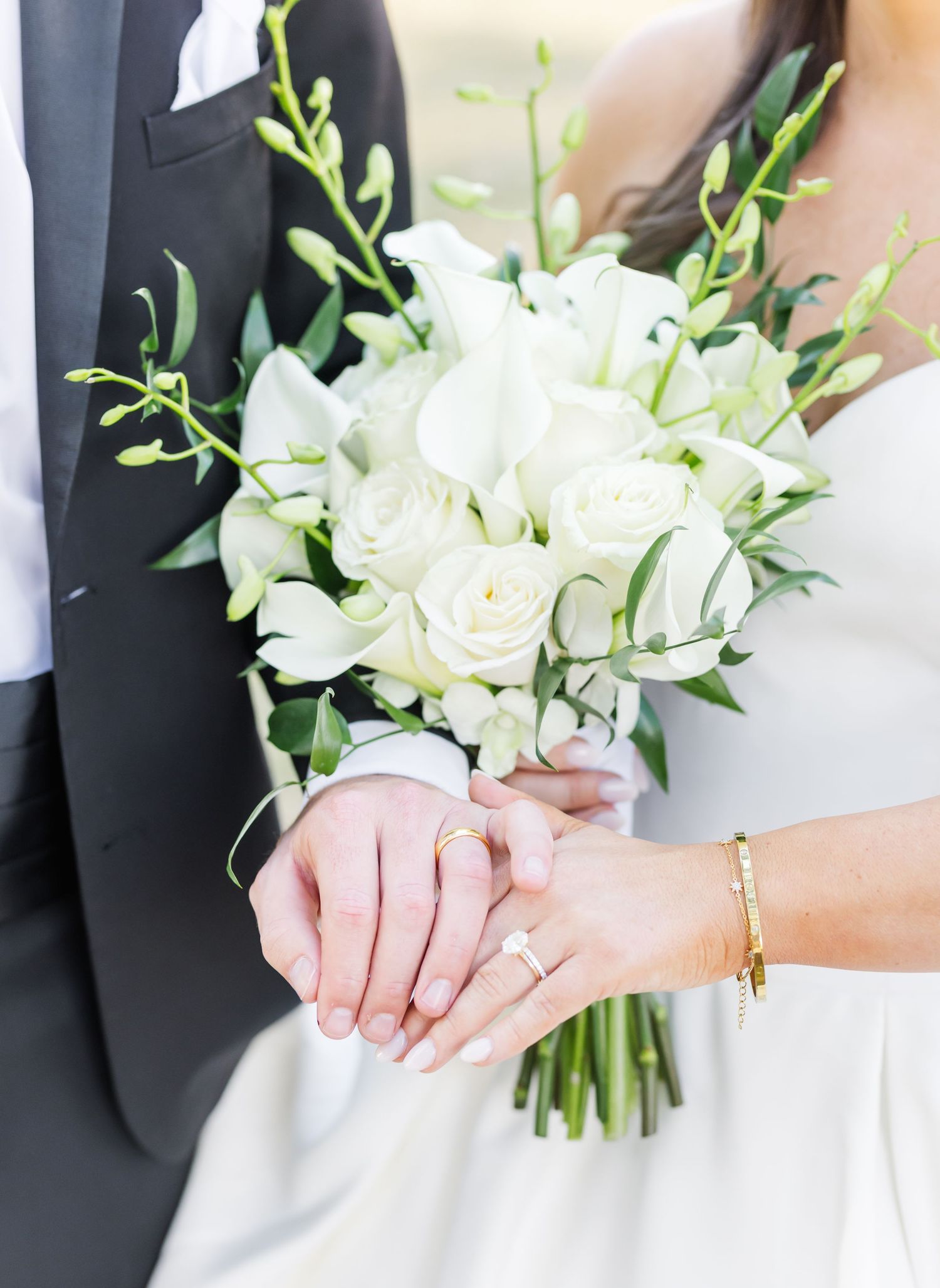 Wedding detail shots of hands holding elegant white bouquets against formal attire.
