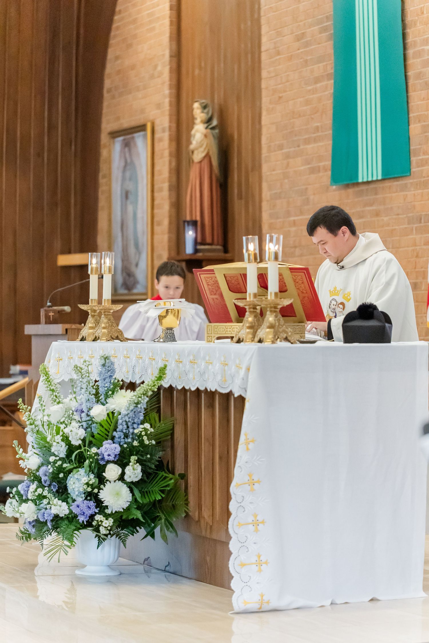 Church altar decorated with white and blue floral arrangements for a wedding ceremony.