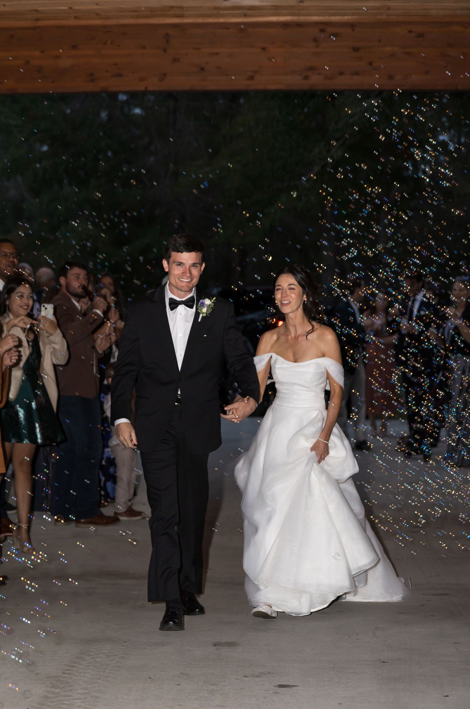 Wedding couple exits venue at night surrounded by celebratory confetti and sparklers.