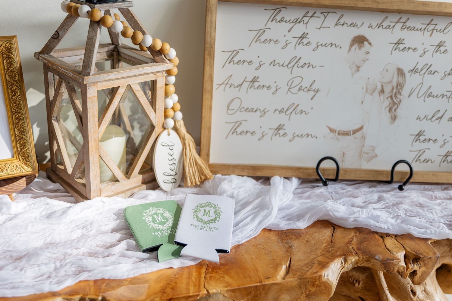 Rustic wedding decor featuring lanterns, candles and handwritten signs arranged on a white tablecloth.