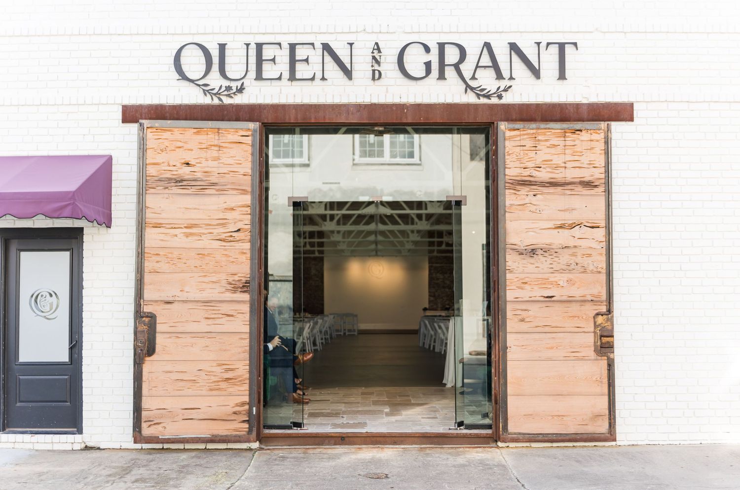 Exterior storefront view of Queen and Grant with wooden door frames and a minimalist white facade.