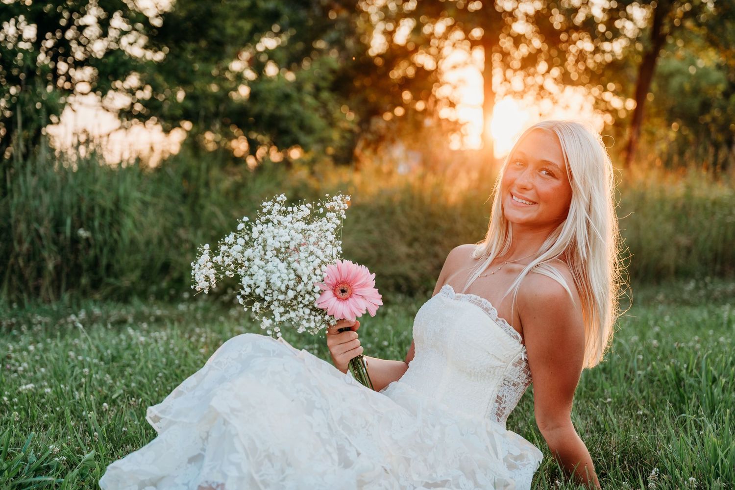 Romantic golden hour photography session showing a flowing white bridal gown against the setting sun.