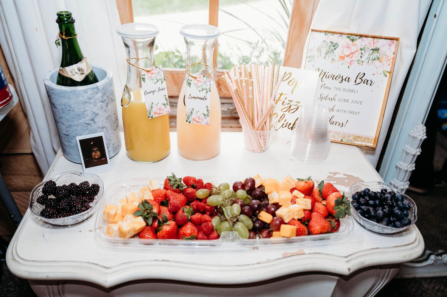 Fresh berries, fruits, and drinks are displayed on a white table at a party or event setting.