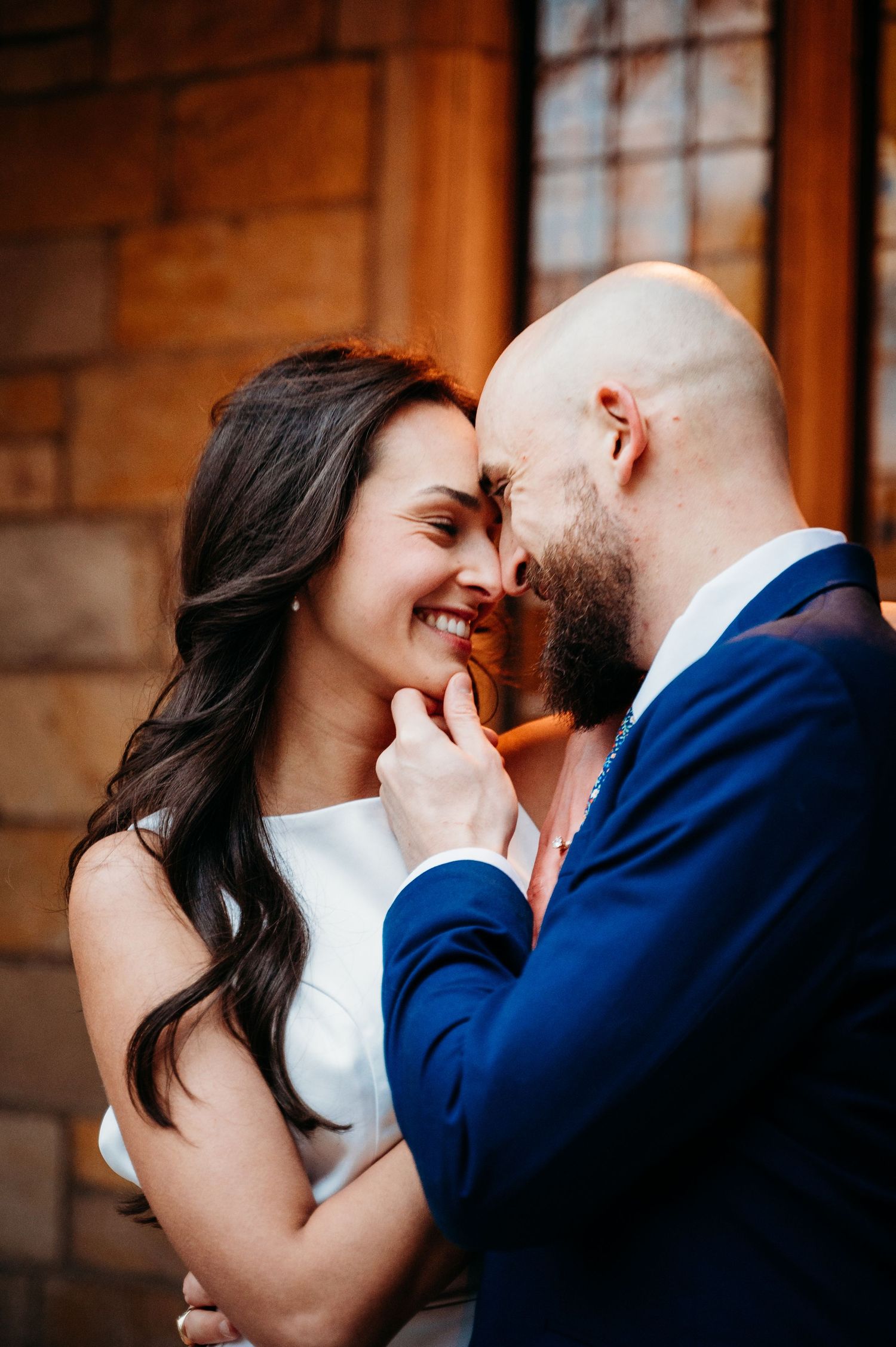 Intimate moment between couple against brick wall background.