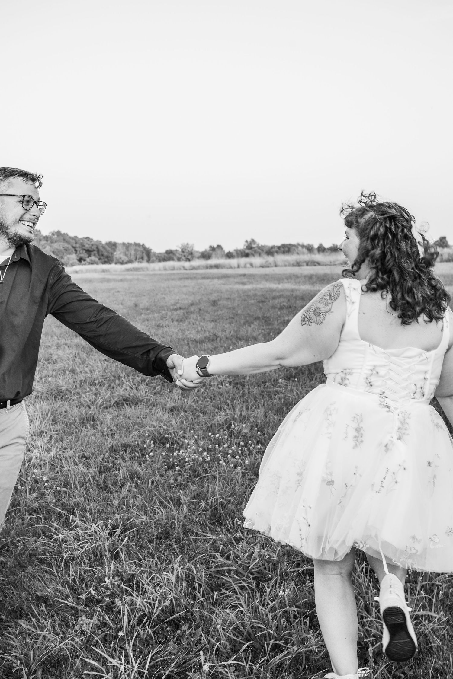 Black and white photograph series of a woman in a flowy white dress dancing and twirling in a grassy field.