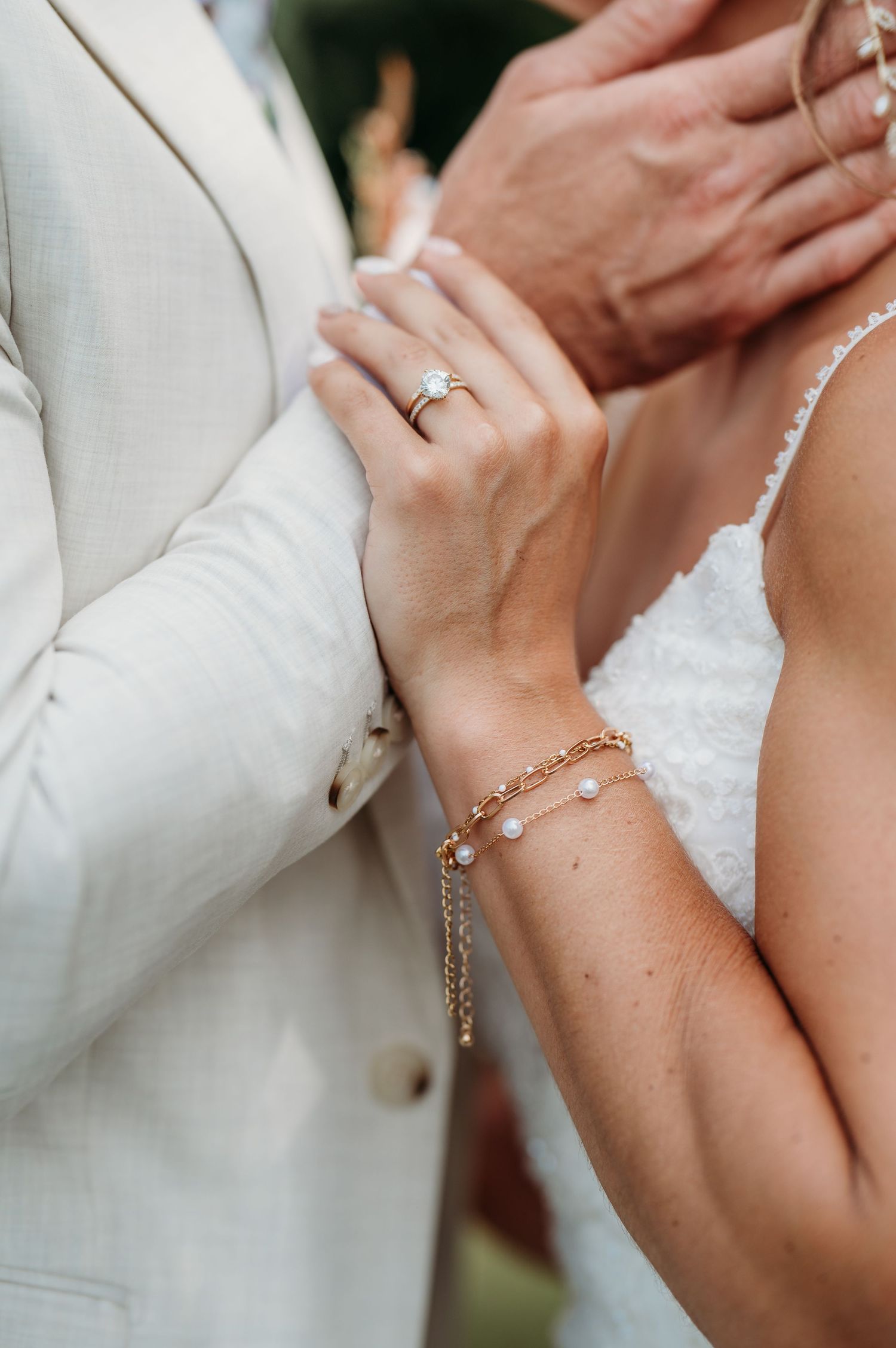 Close-up of elegant bridal jewelry and hands during wedding ceremony.