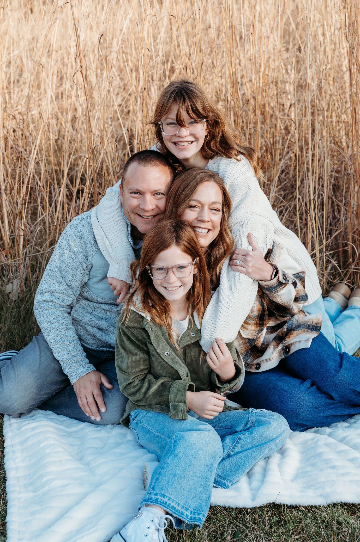 Happy family portrait outdoors with their dog against tall wheat grass.