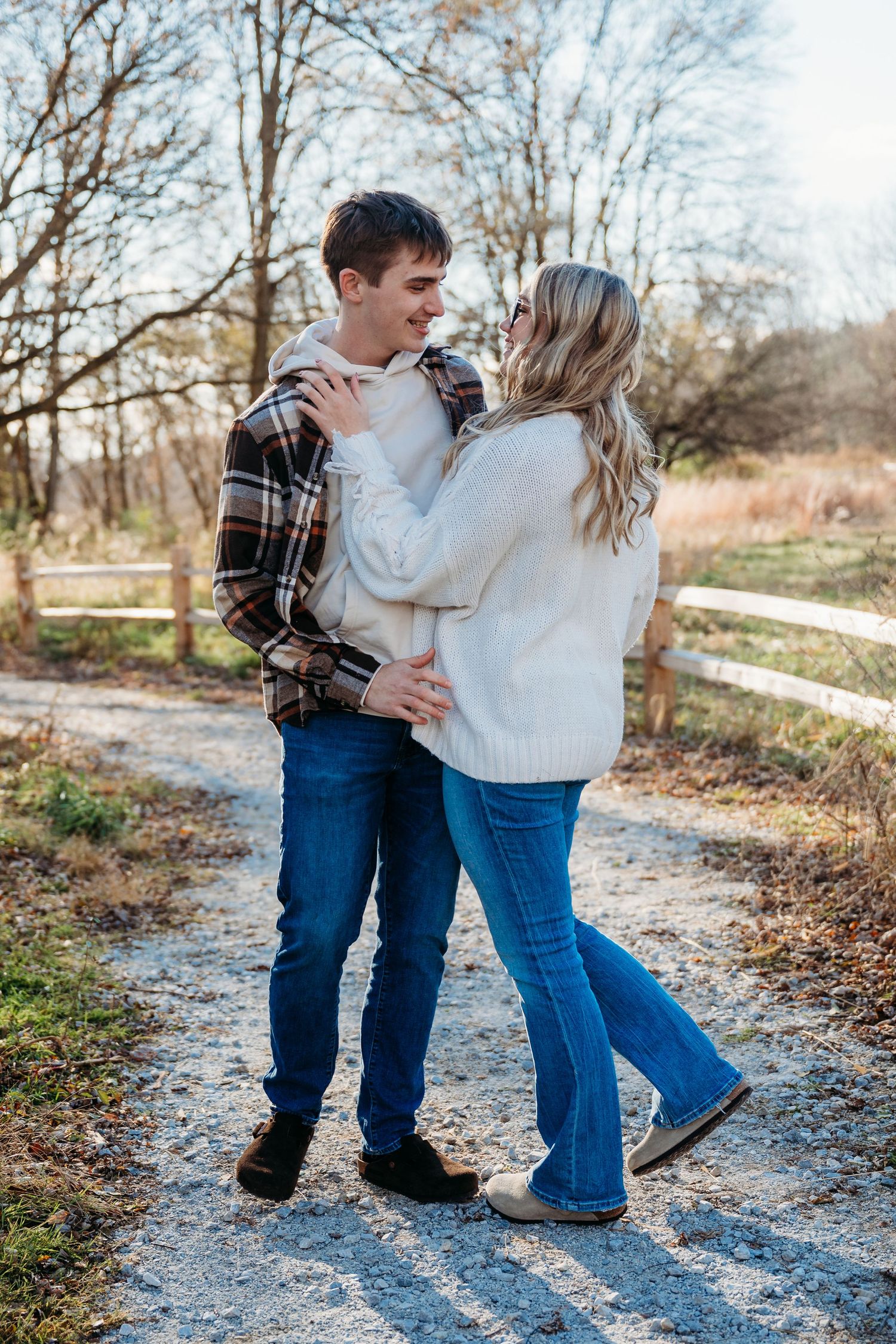 Couple walking together on a gravel path through a winter landscape wearing casual clothing and boots.