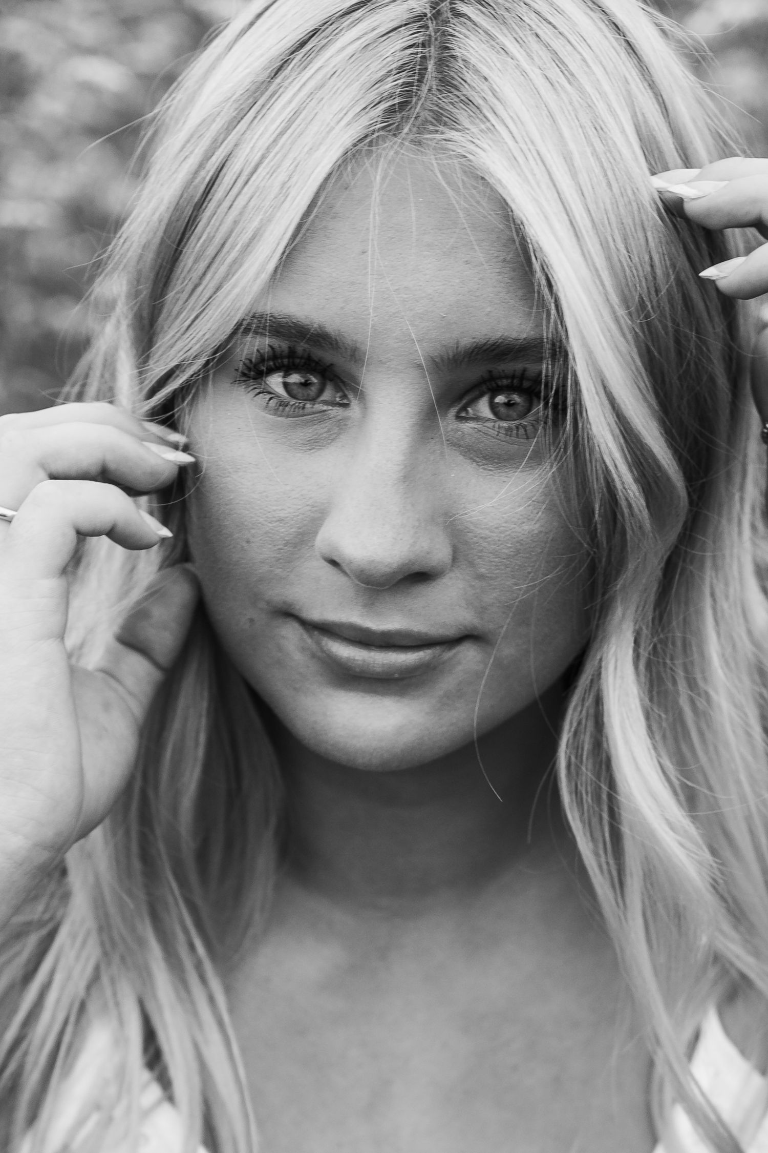A black and white portrait of a person with blonde hair and striking eyes photographed in a natural soft lighting.