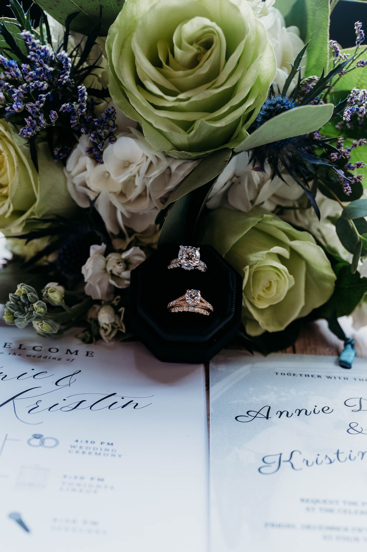 Wedding invitation details with green roses and purple flowers arranged elegantly on white paper.