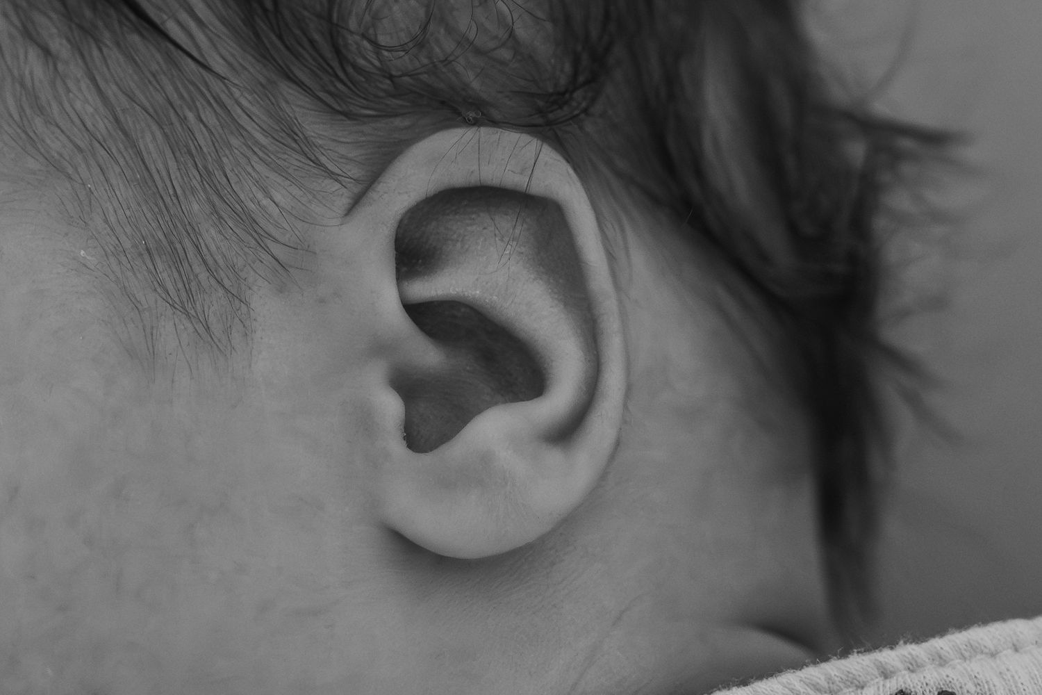 Close-up view of a human ear showing detailed anatomical features in black and white.